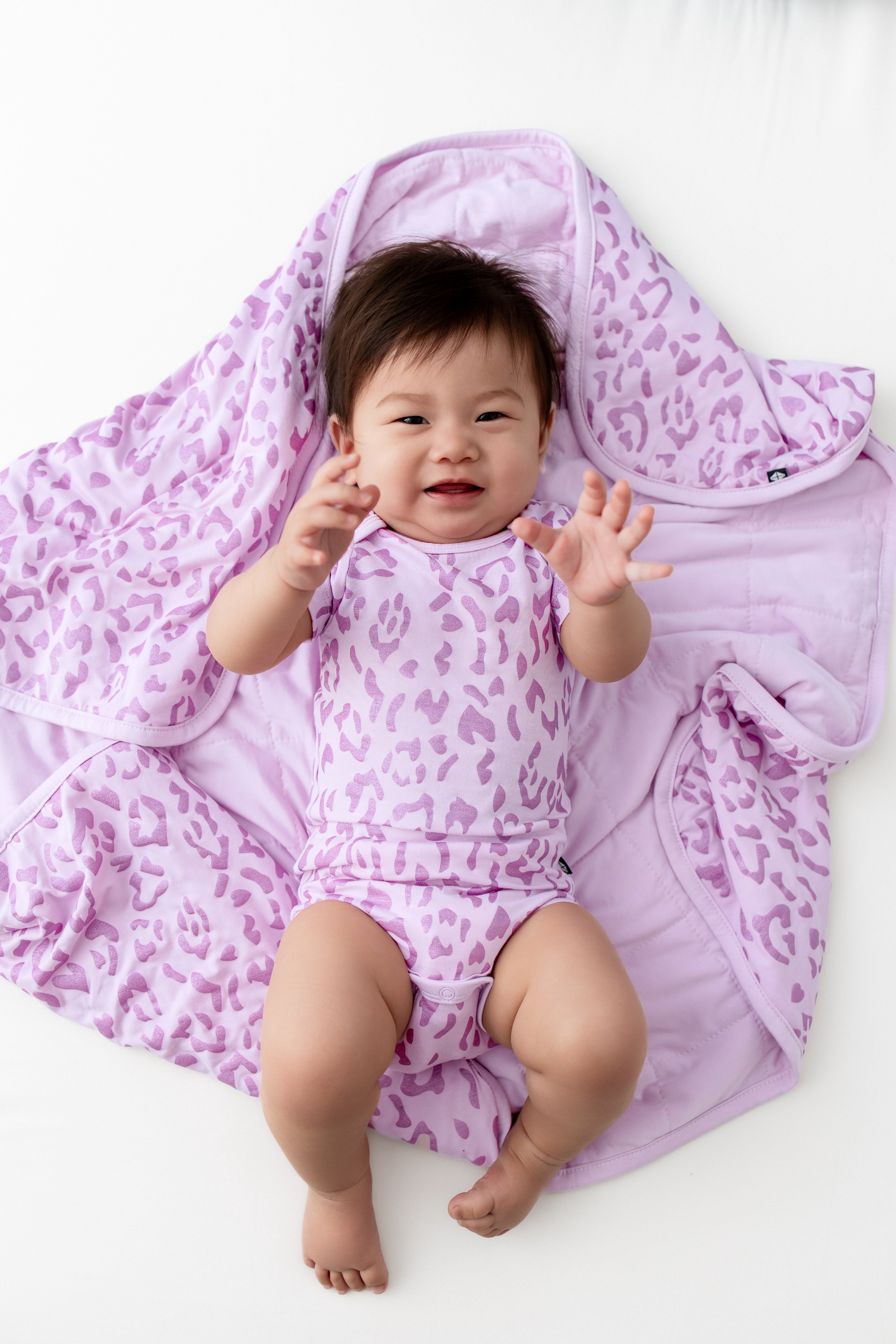 Baby lying over a Baby Blanket with Thistle Leopard print on a white background