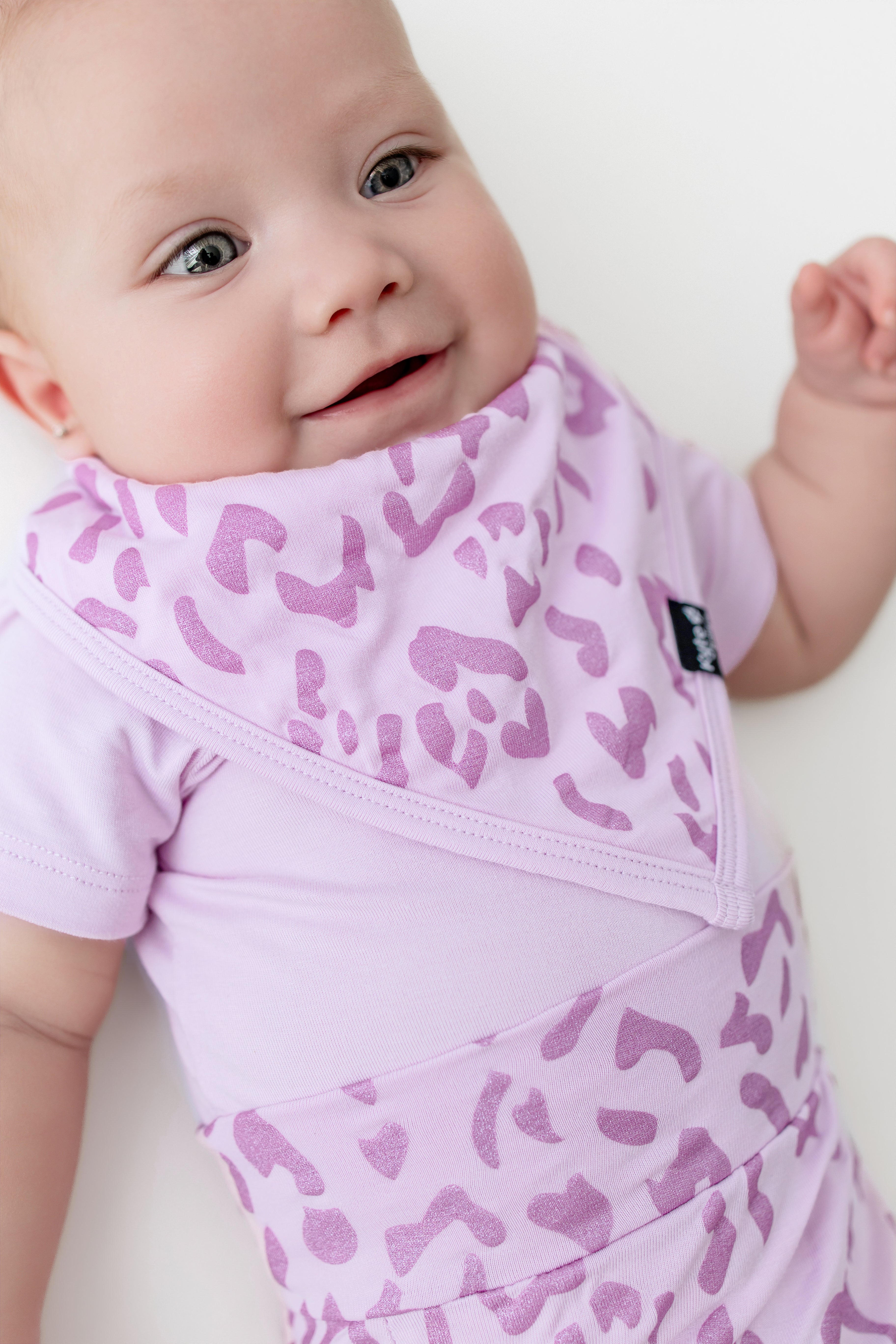Baby wearing a Thistle Leopard print Bib with a similar print bummies on a white background