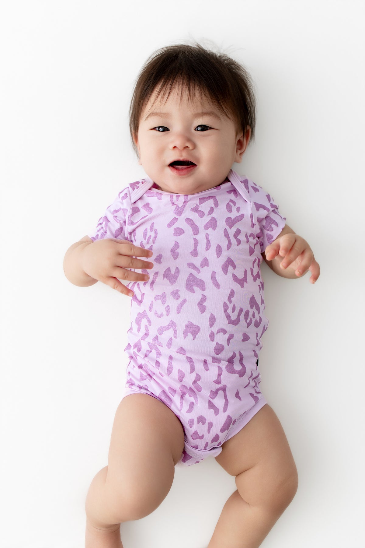 Baby wearing a Thistle Leopard print Bodysuit on a white background