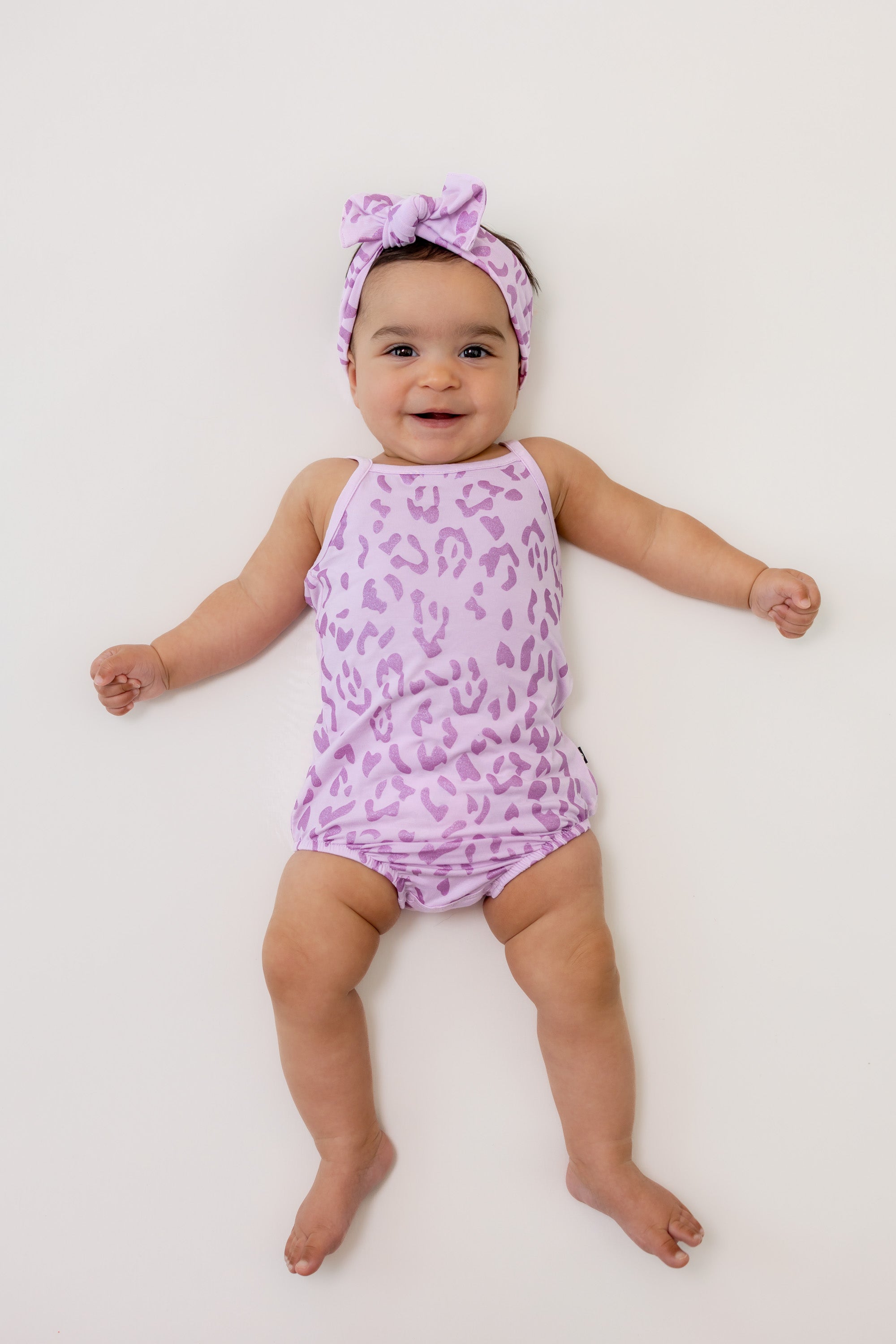 Baby wearing Thistle Leopard print Spaghetti Strap Leotard and bow headband on a white background