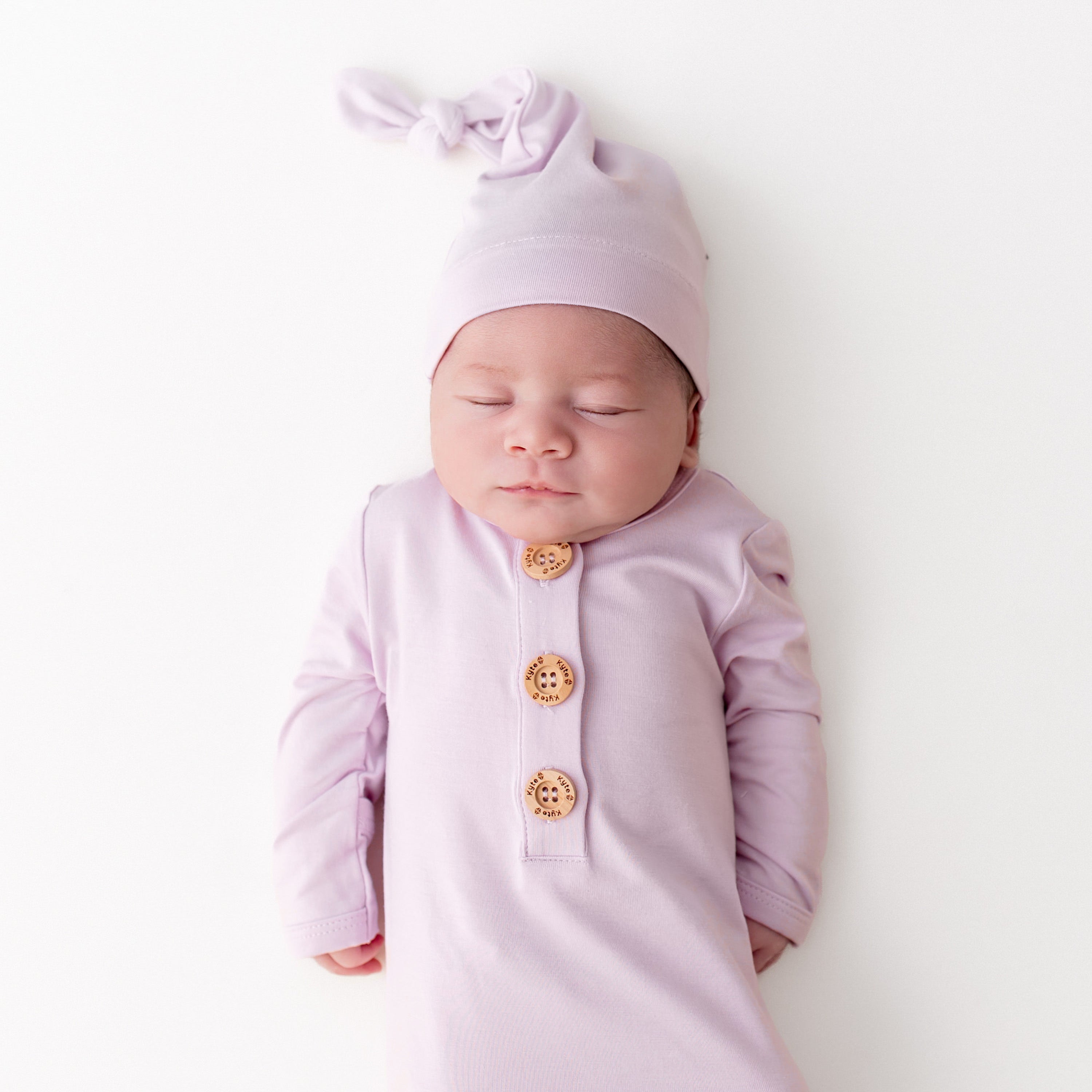 Close up of sleeping newborn wearing the Knotted Gown with Hat Set in Thistle