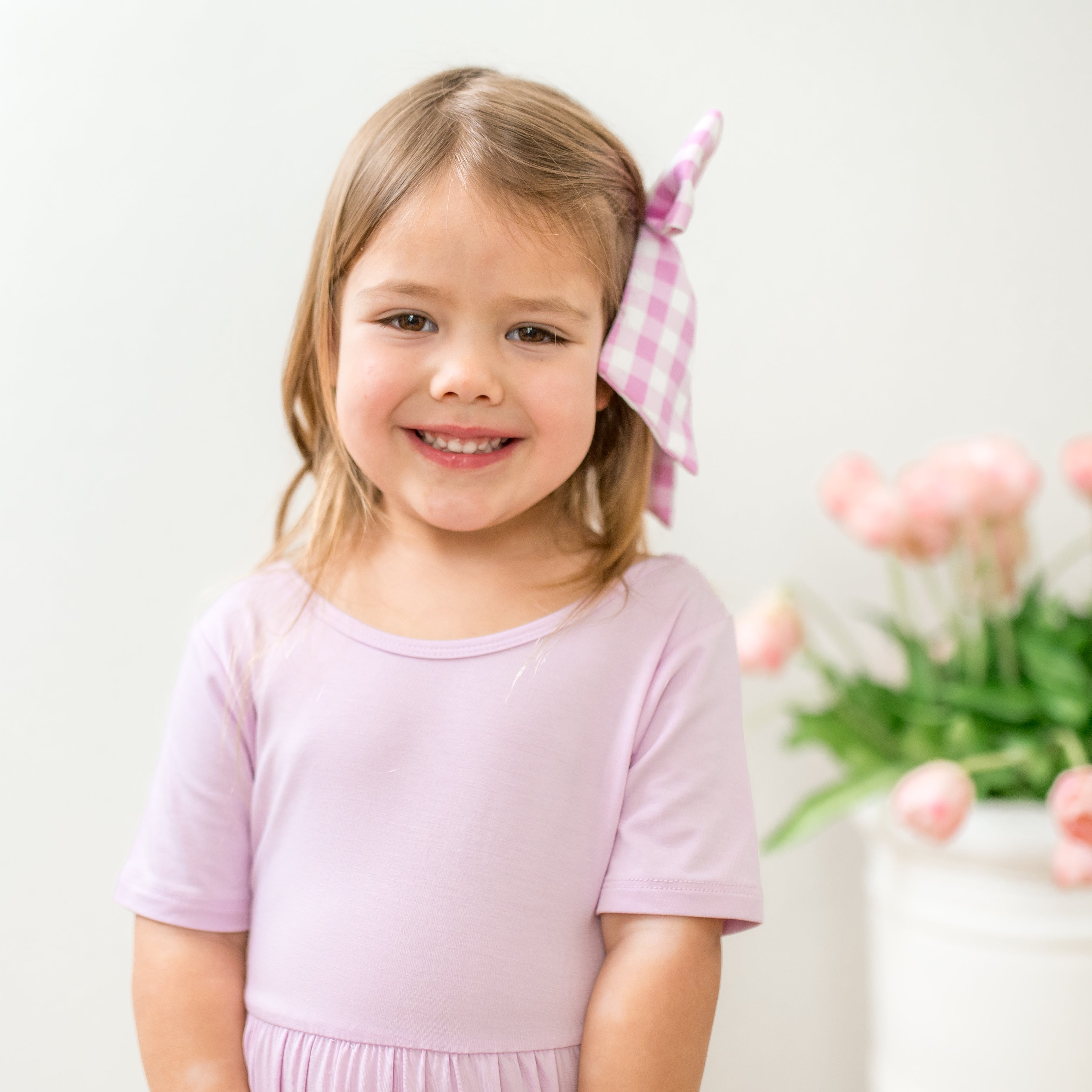 Young girl in a purple dress with a headband, smiling at the camera.
