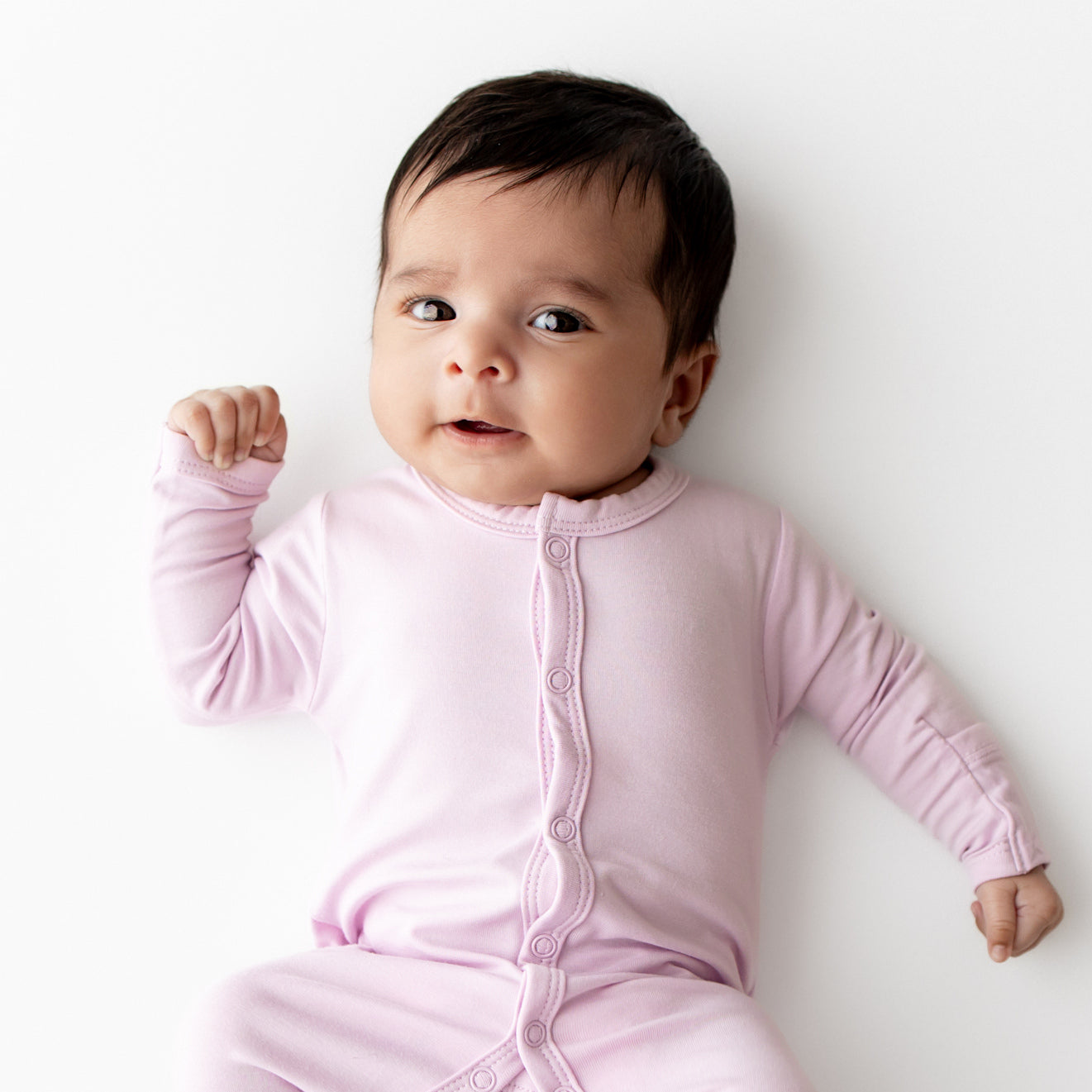 Baby wearing a purple snap onesie against a white background