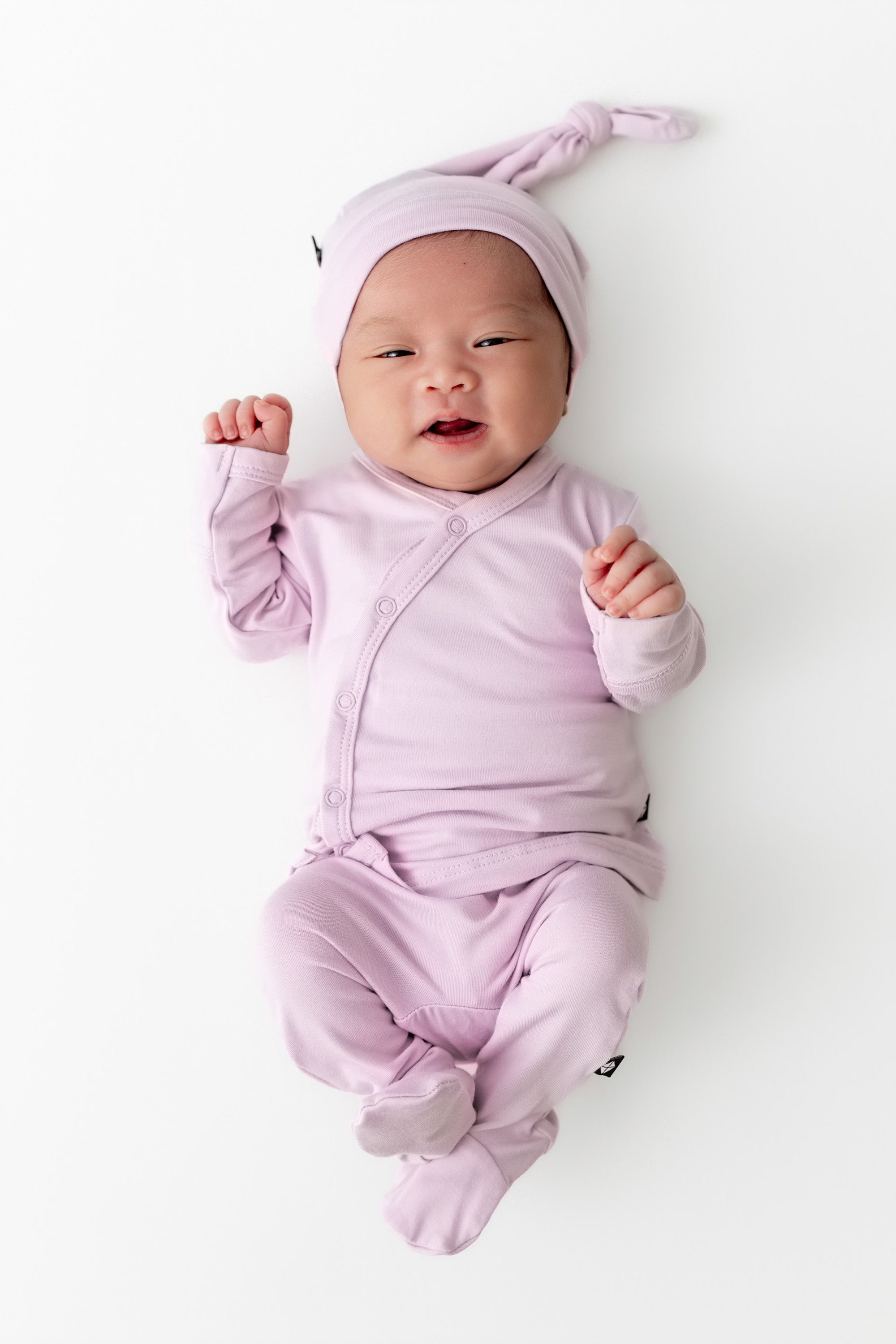 Baby wearing a light purple outfit and hat on a white background