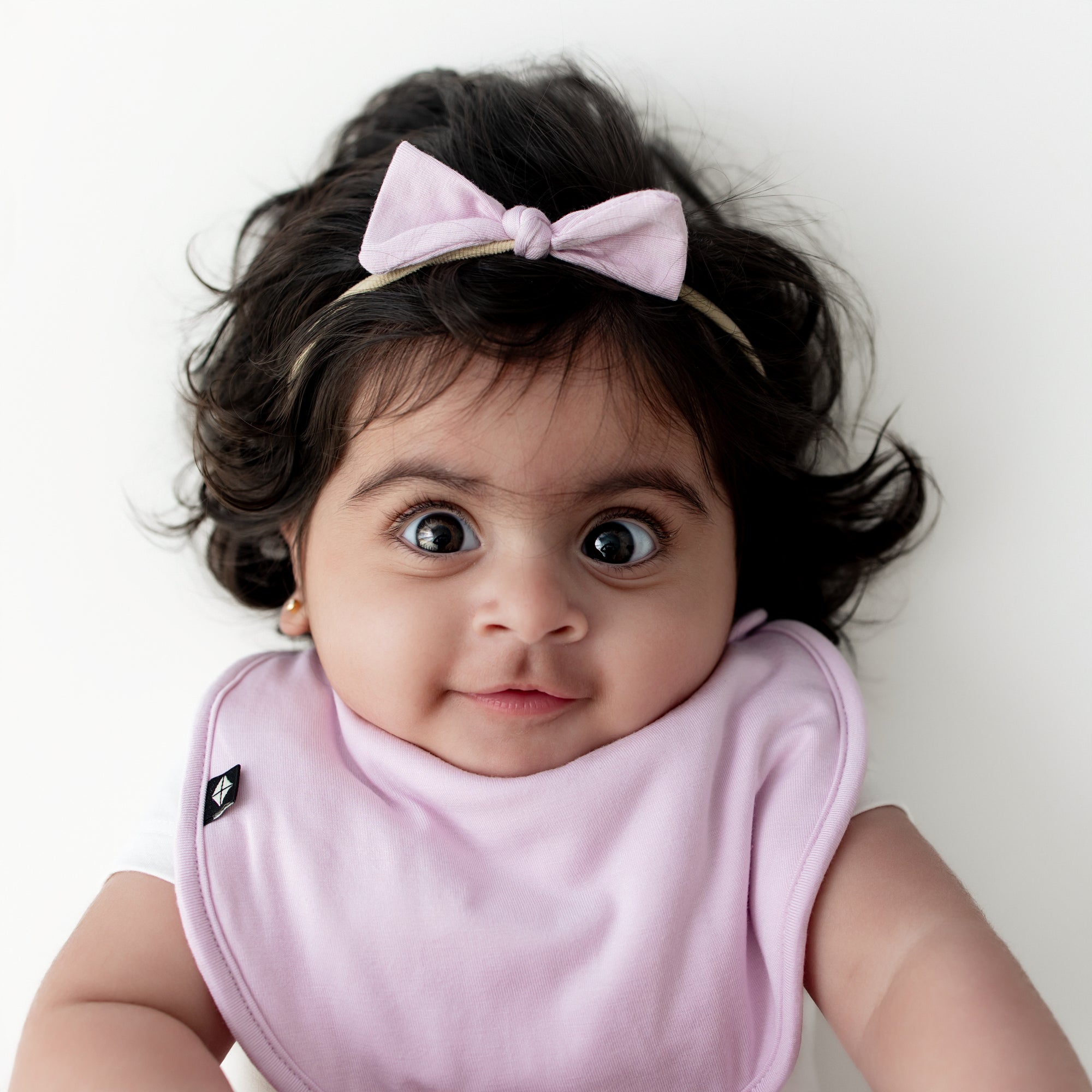 Young infant wearing the Tiny Nylon Bow in Thistle with matching cushy bib