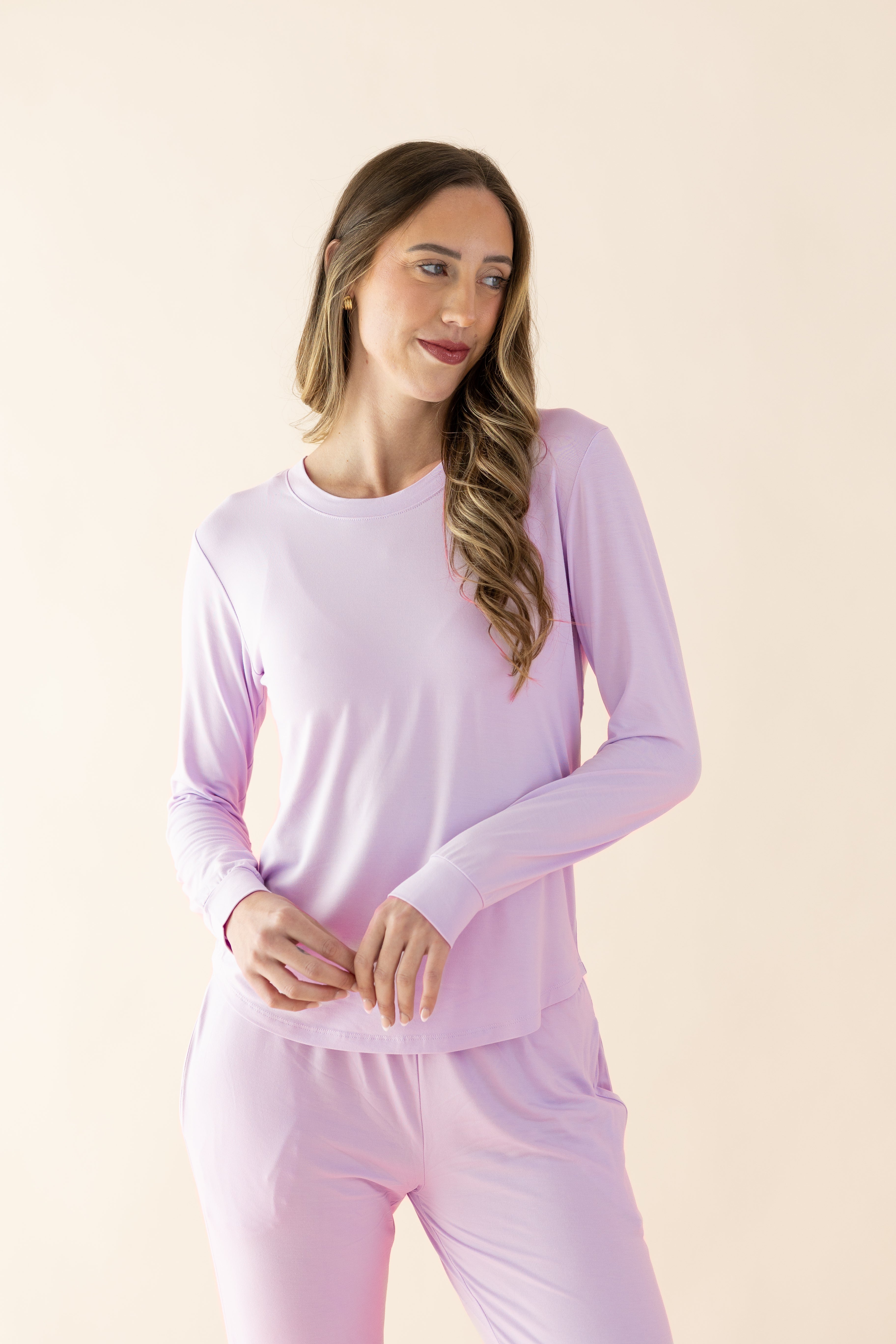 Woman wearing a purple long-sleeve top and pants on a beige background