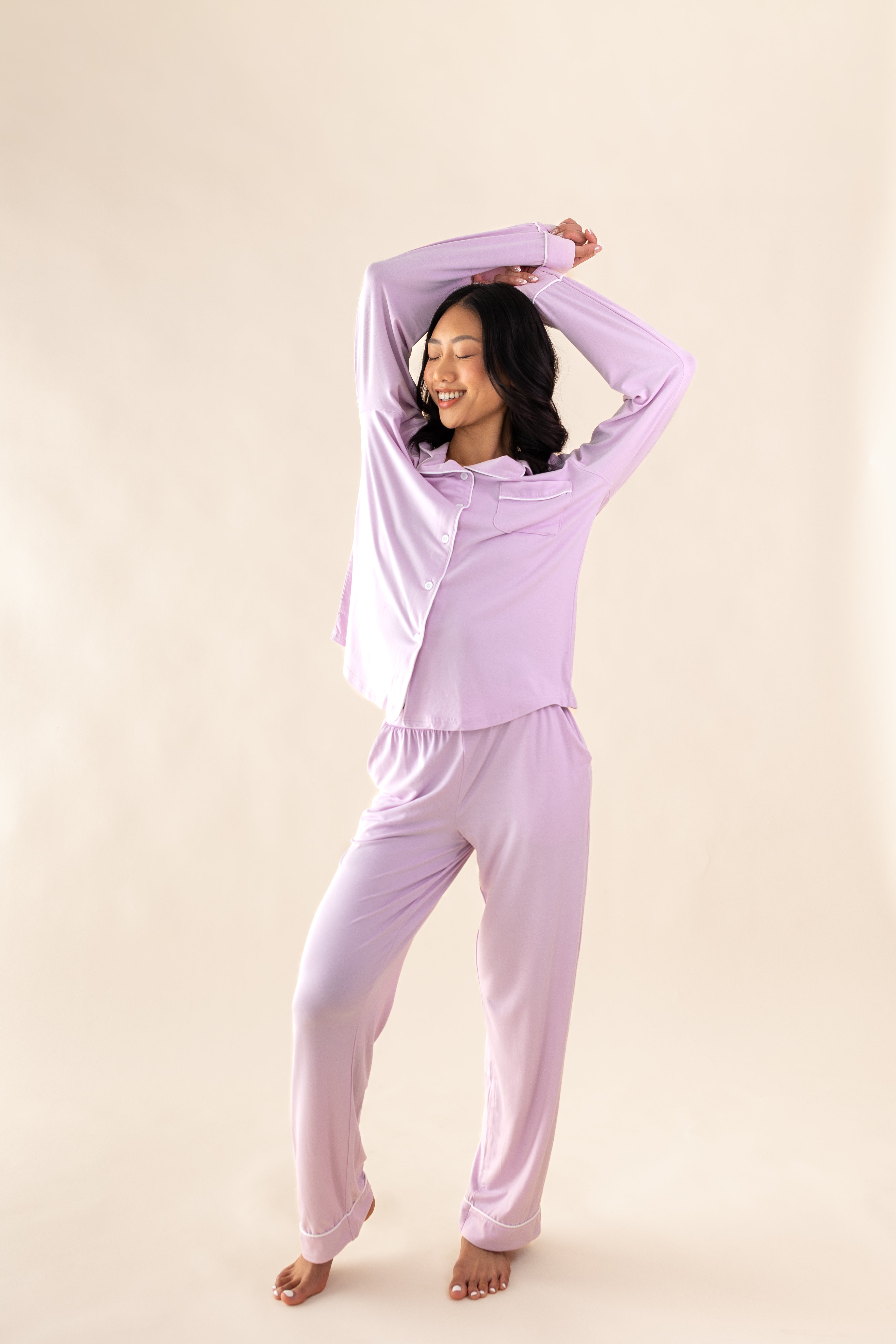 Woman wearing a lavender pajama set against a beige background