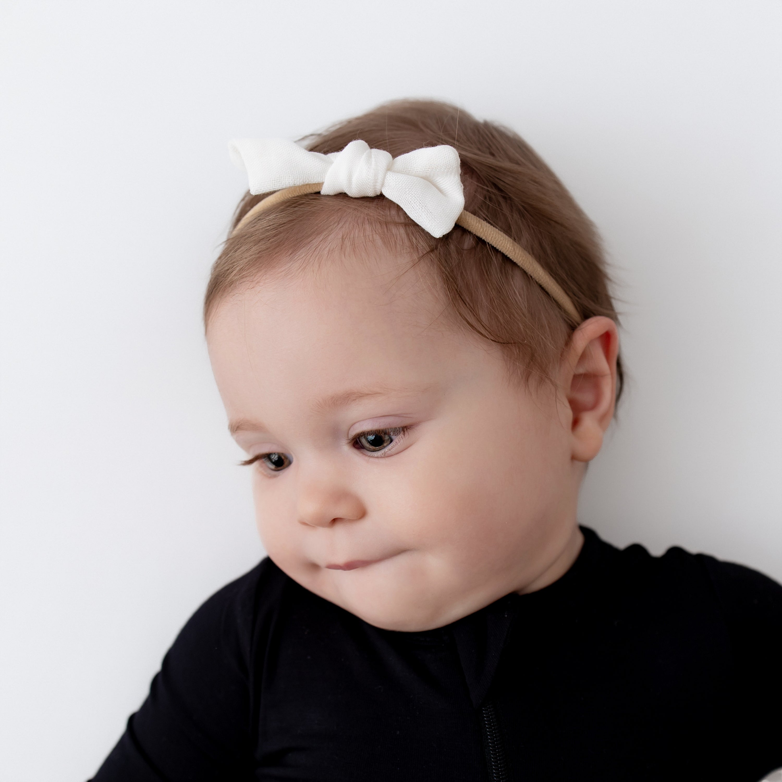 Baby wearing Bamboo Muslin Tiny Bow in Cloud with midnight romper