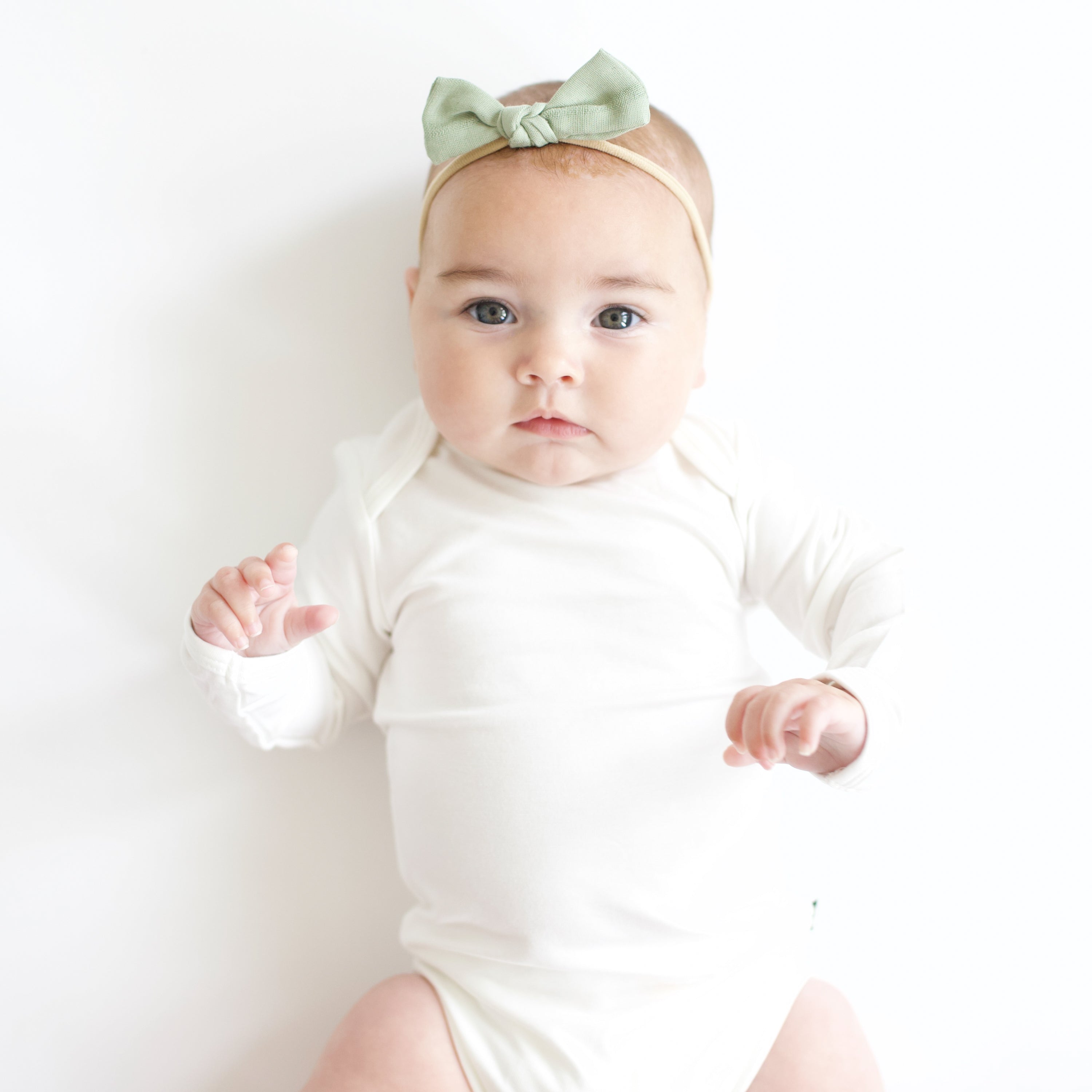 Baby wearing Bamboo Muslin Tiny Bow in Jojoba and cloud bodysuit