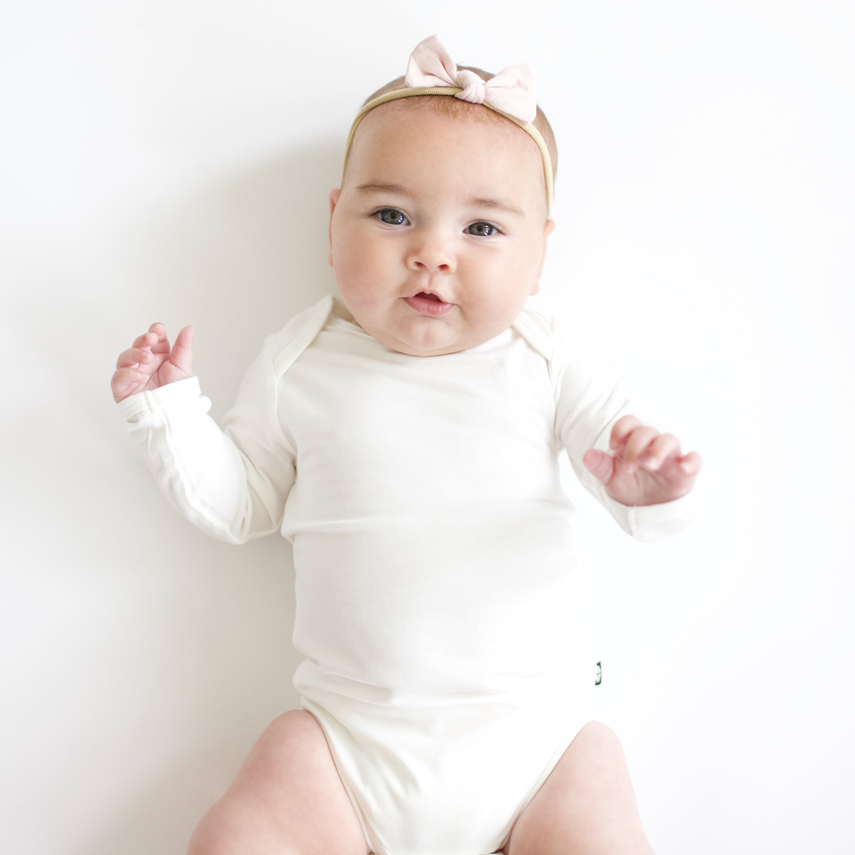 Baby girl wearing a Tiny Nylon Bow in Blush and a Long Sleeve Bodysuit in Cloud