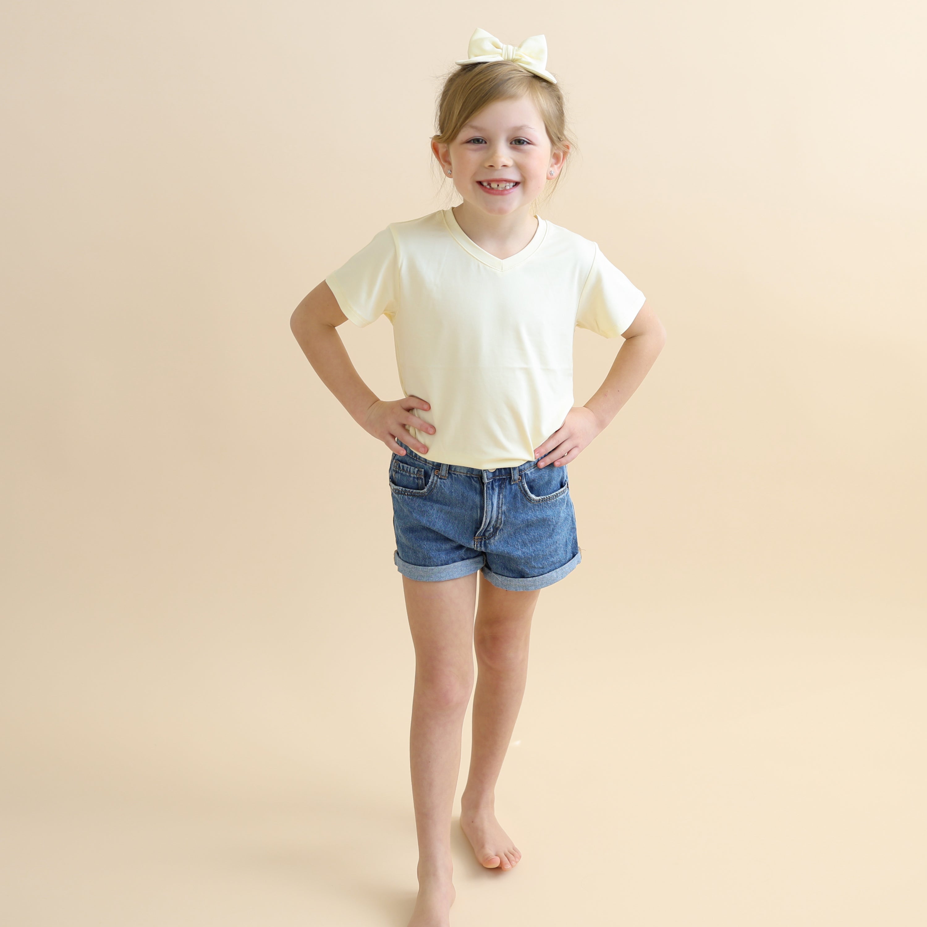 Young girl wearing the Toddler V-Neck Tee in Chamomile paired with jean shorts