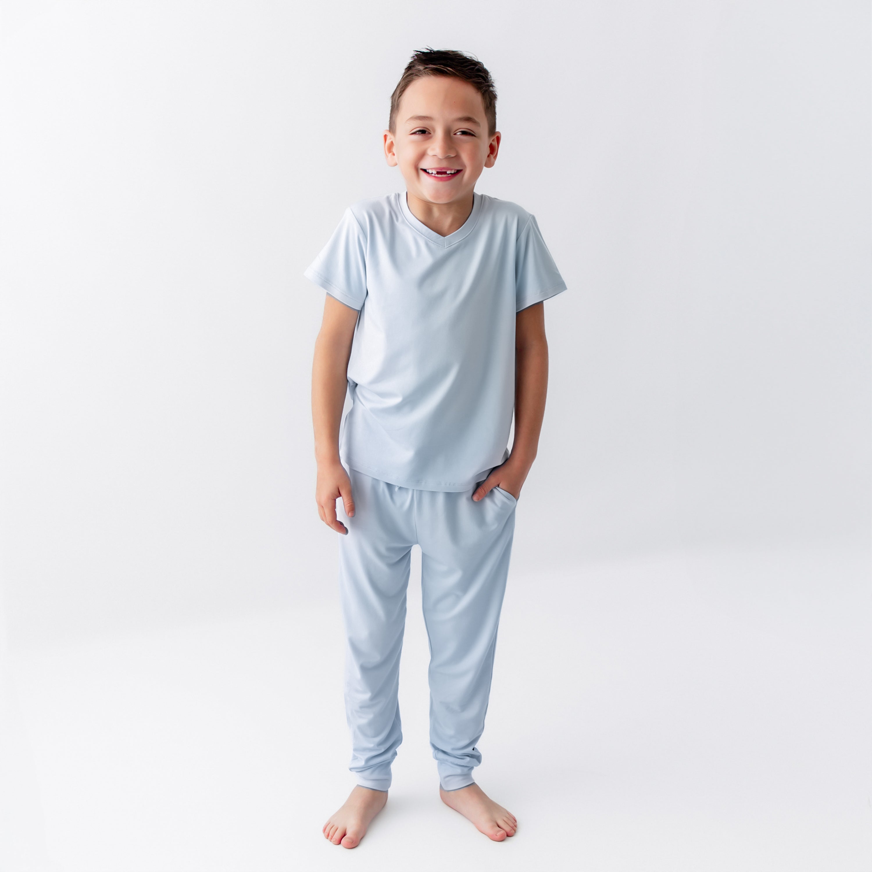 Young boy wearing the Toddler Jogger Pant in Breeze paired with a matching toddler V-neck standing in front of a white background