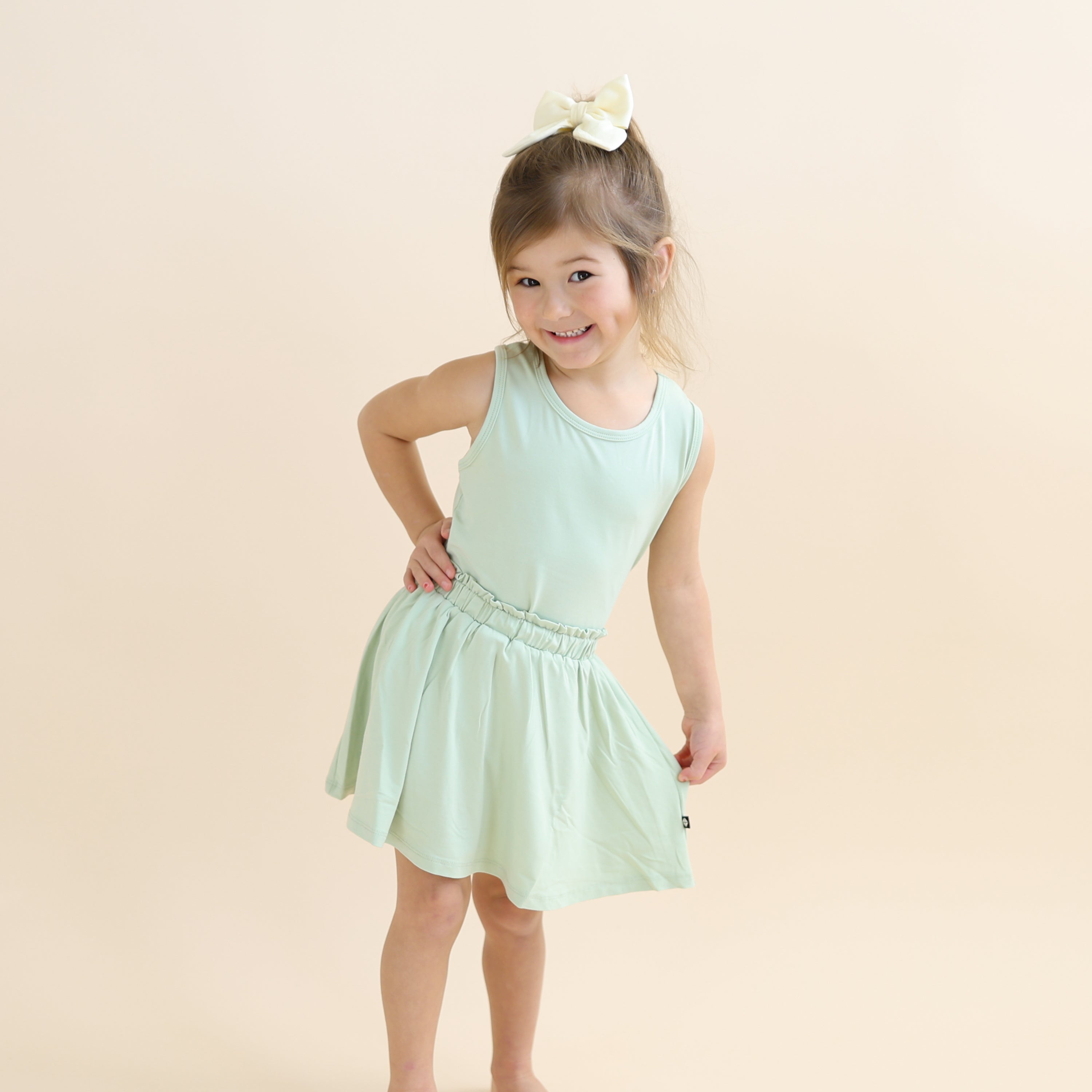 Young girl posing wearing the Toddler Skort in Basil and matching toddler tank top