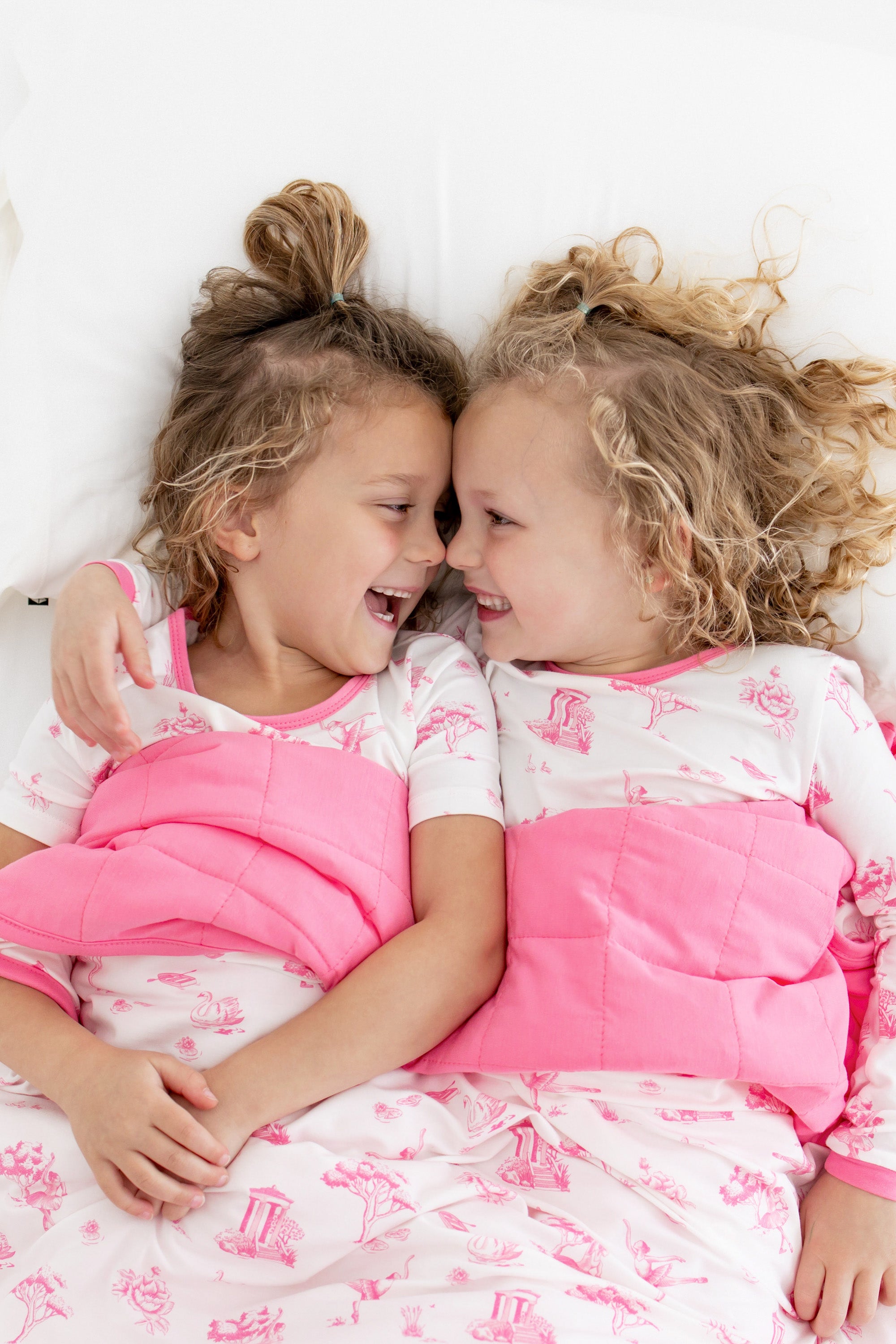 2 toddler girls snuggling in toile blanket
