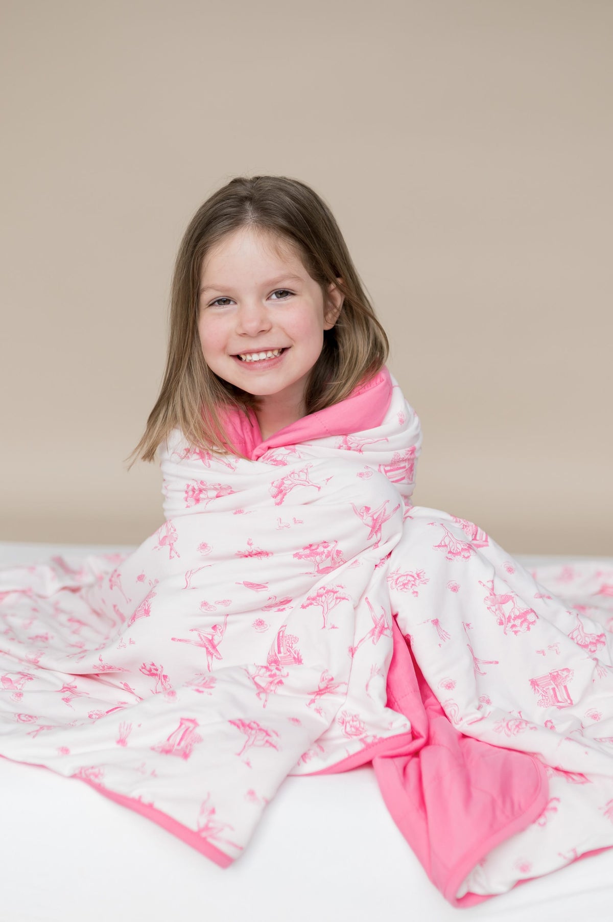Young girl sitting with the Youth Blanket in Toile Ballet 1.0 wrapped around her