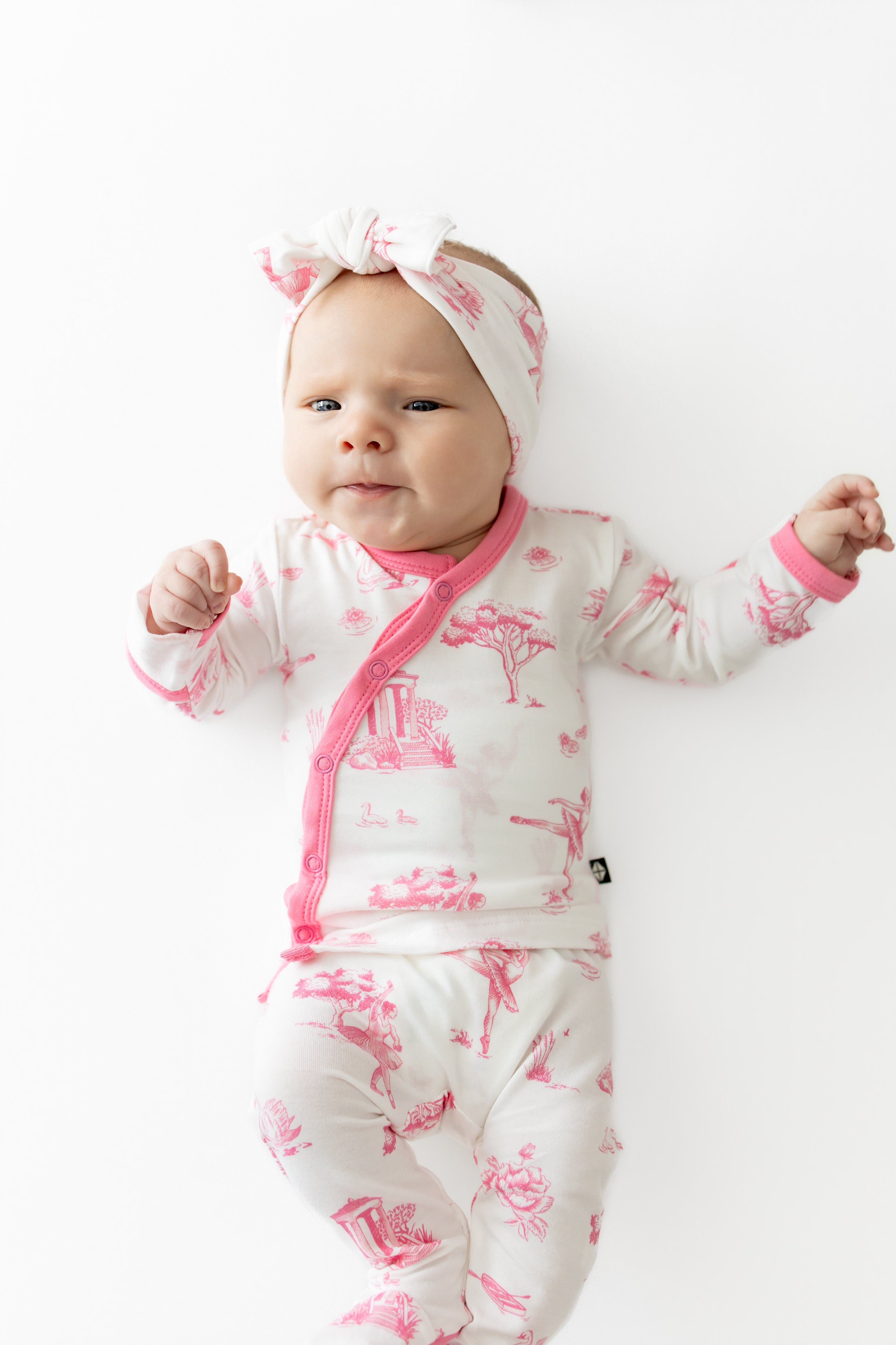 Close up of newborn laying on a white surface wearing the Take Me Home Set with Bow in Toile Ballet