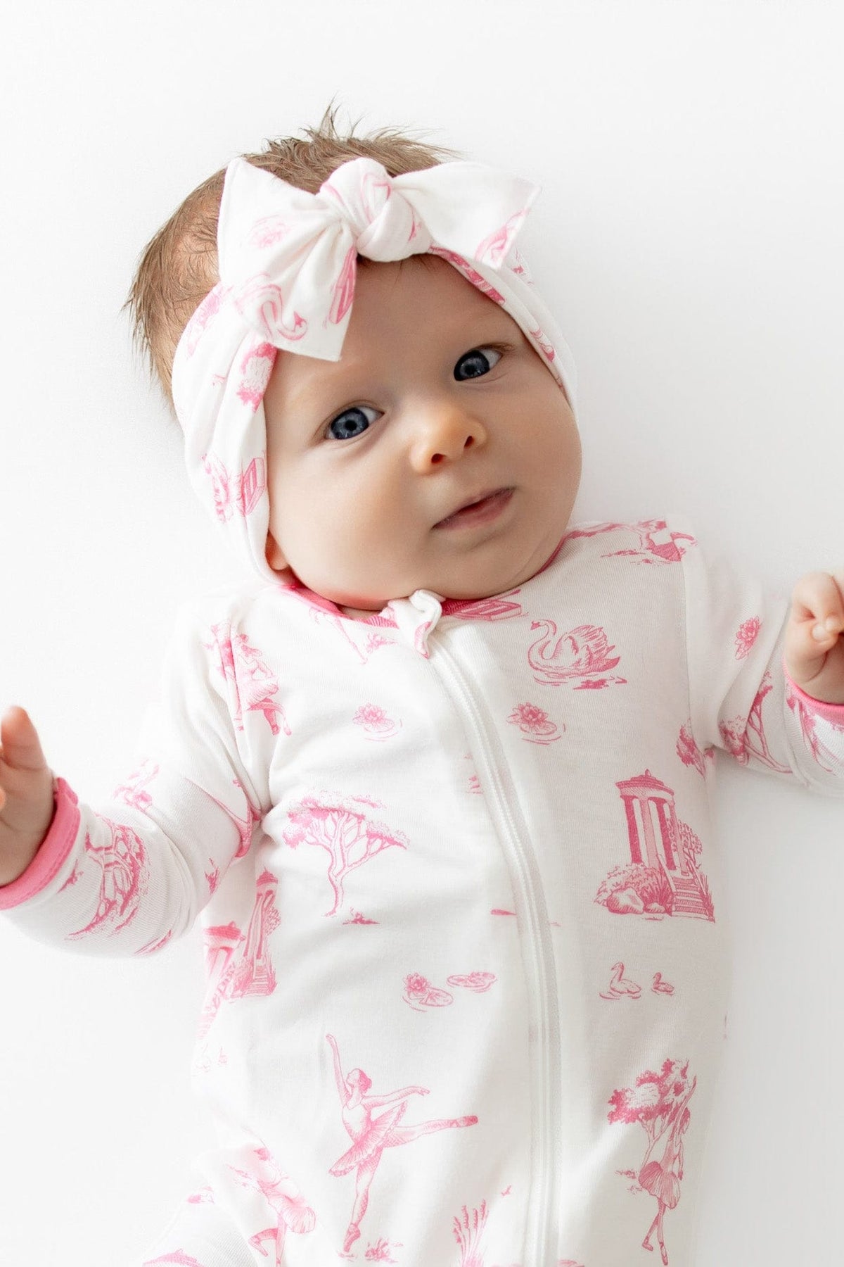 Close up of infant wearing the Knotted Bow Headband in Toile Ballet and matching romper