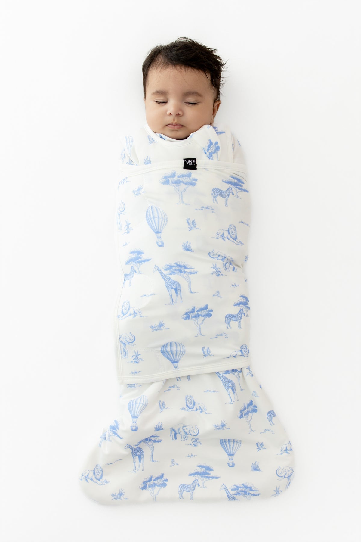 Sleeping newborn swaddled in the Sleep Bag Swaddler in Toile Safari 1.0