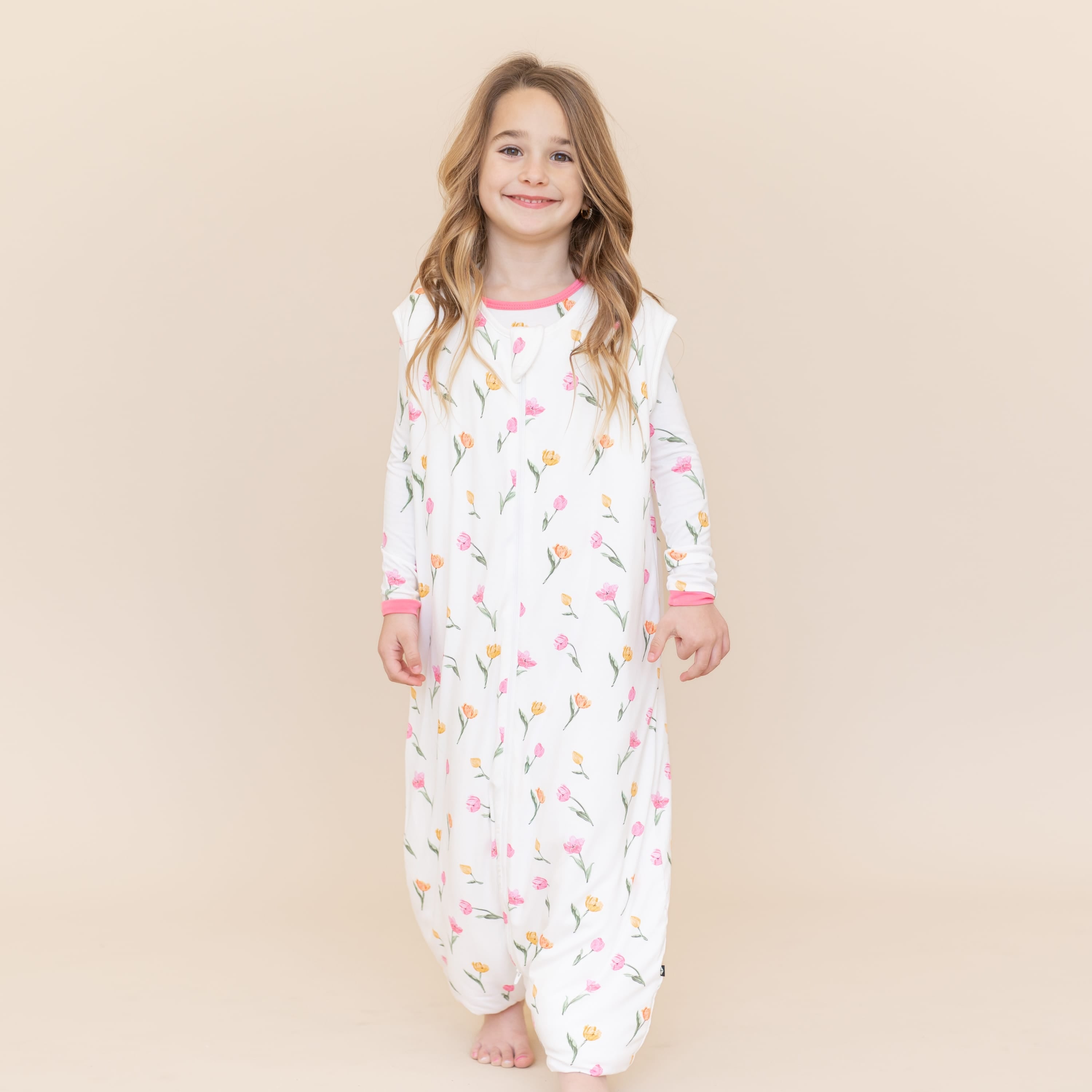 Young girl walking modeling the Sleep Bag Walker in Tulip 1.0 with matching long sleeve toddler pajamas on underneath