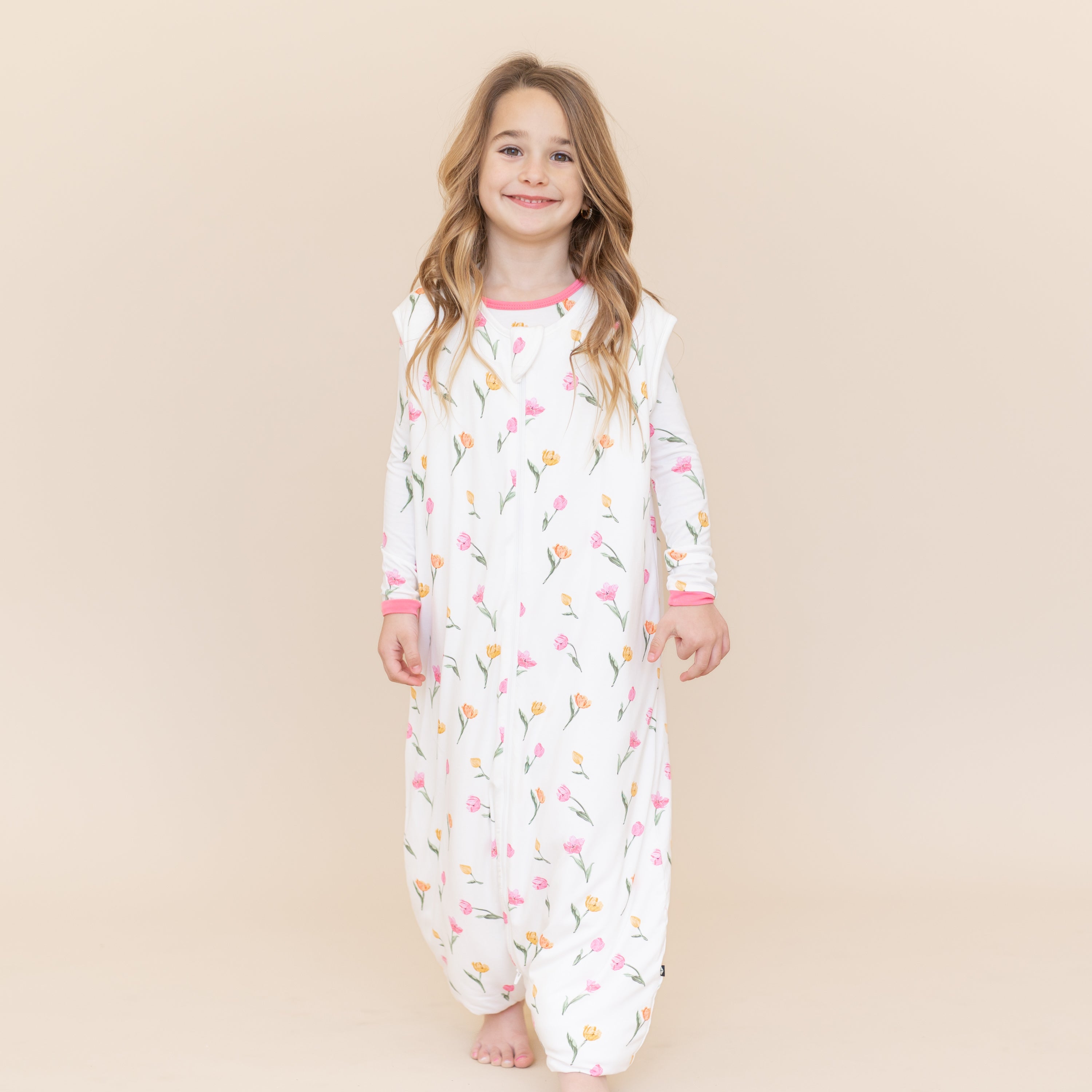 Young girl walking modeling the Sleep Bag Walker in Tulip 1.0 with matching long sleeve toddler pajamas on underneath