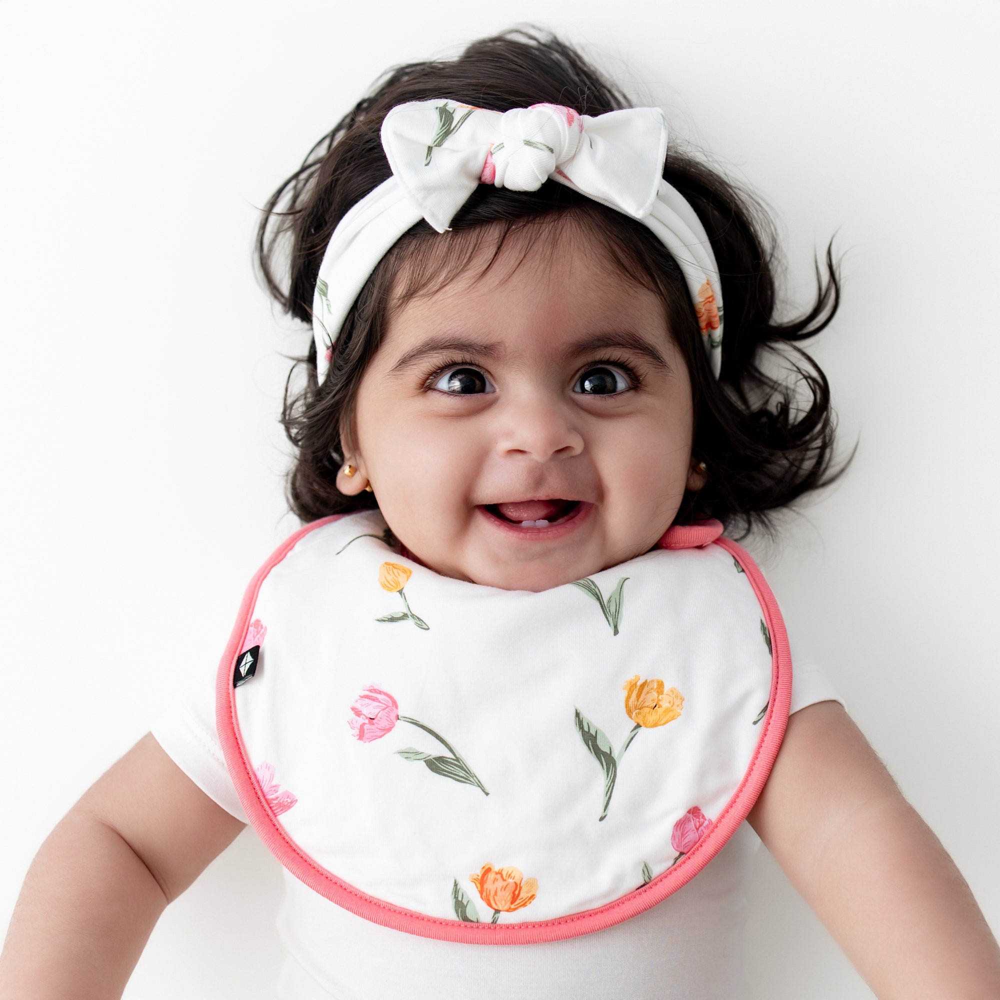 Close up of infant wearing the Cushy Bib in Tulip