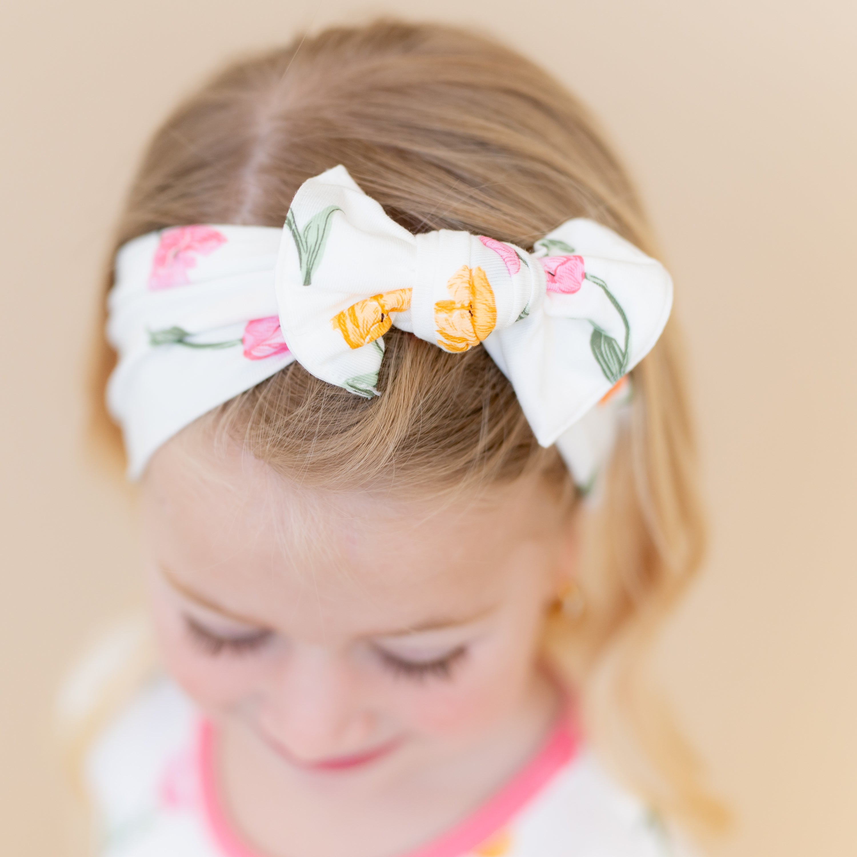 Close up of the Knotted Bow Headband in Tulip shown in the hair of a young girl
