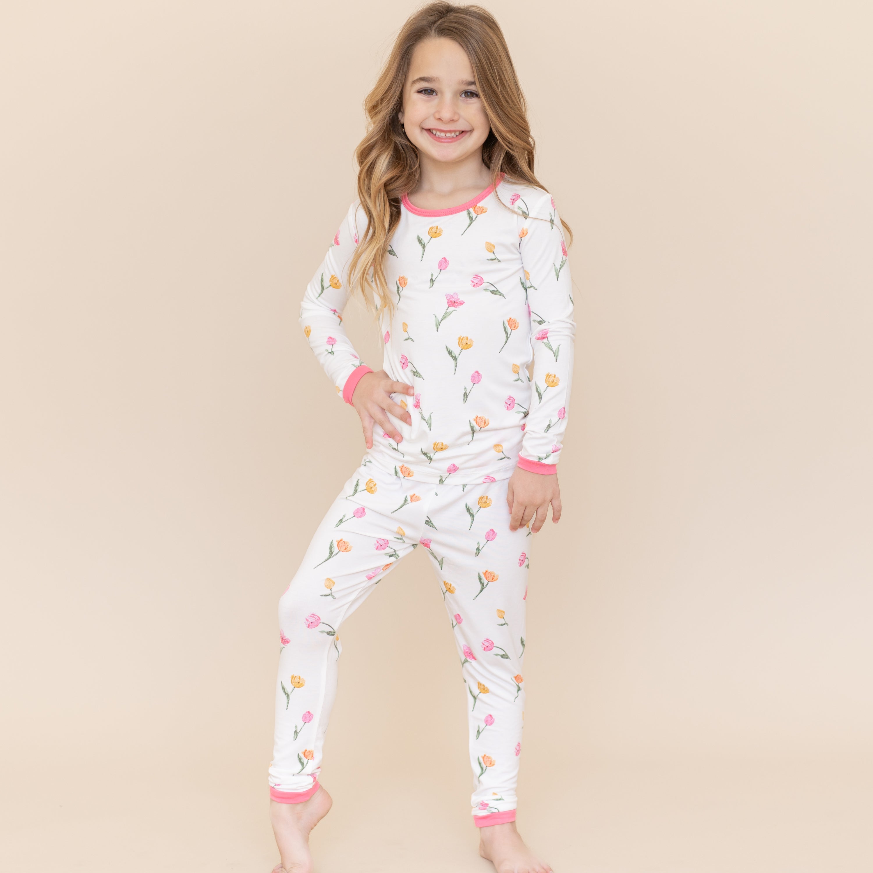 Young girl modeling the Long Sleeve Pajamas in Tulip standing in front of a light neutral background