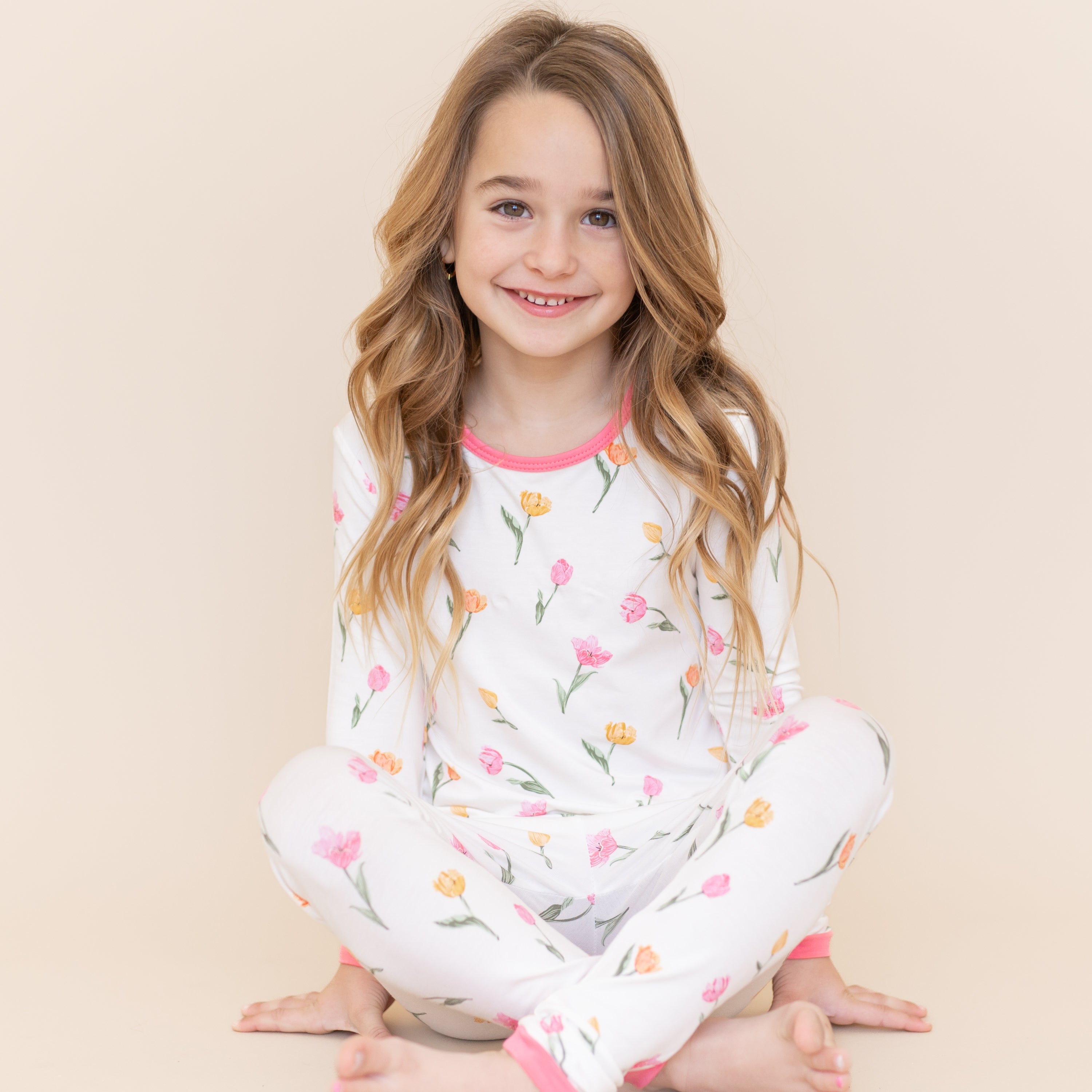 Young girl sitting on the floor wearing the Long Sleeve Pajamas in Tulip