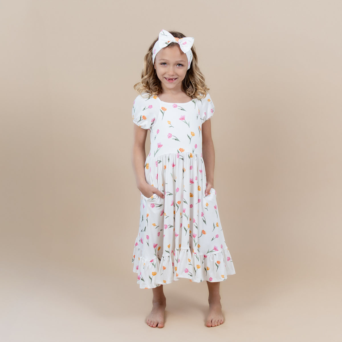 Young girl posing with her hands in the pocket of the Puff Sleeve Twirl Dress in Tulip