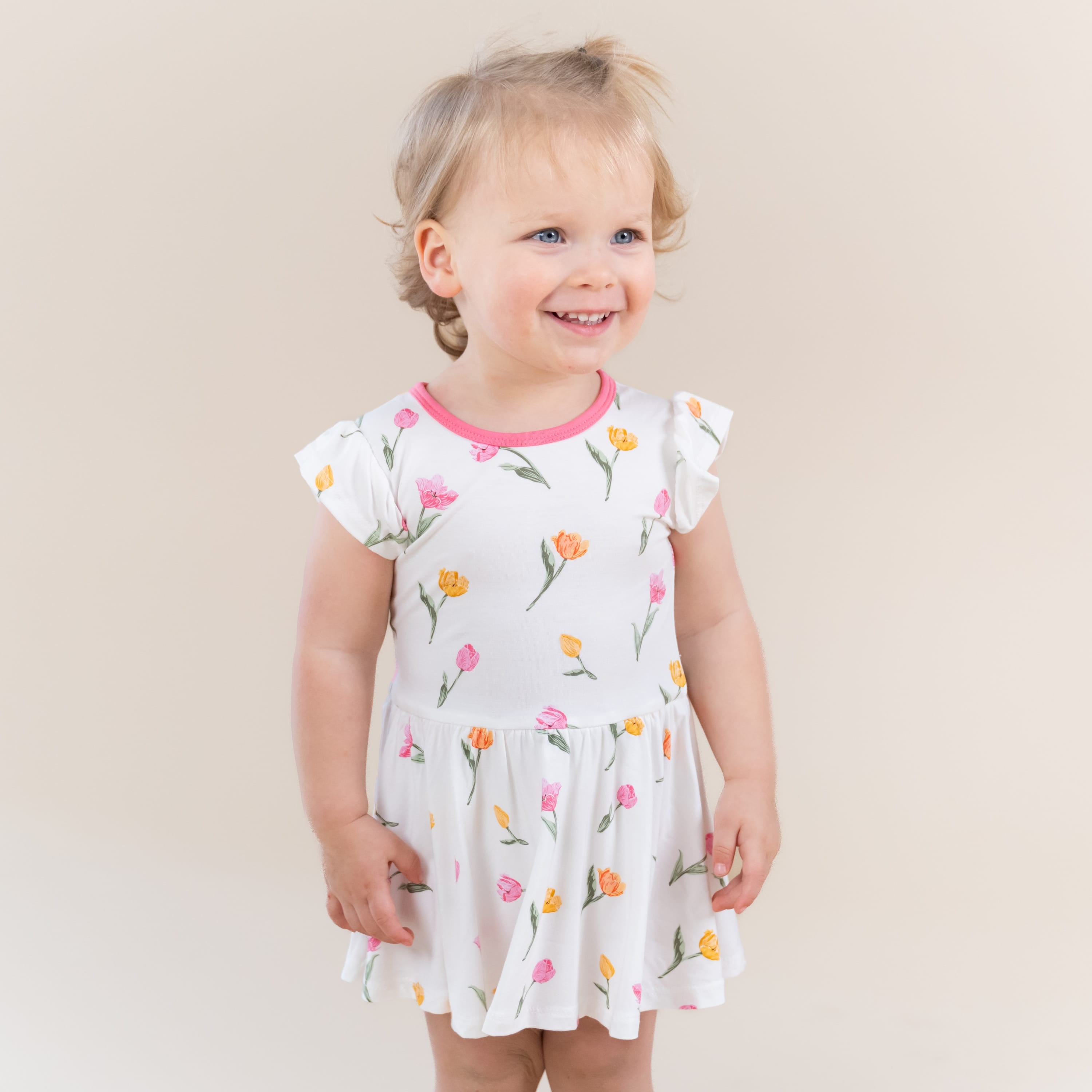 Young smiling toddler modeling the Twirl Bodysuit Dress in Tulip