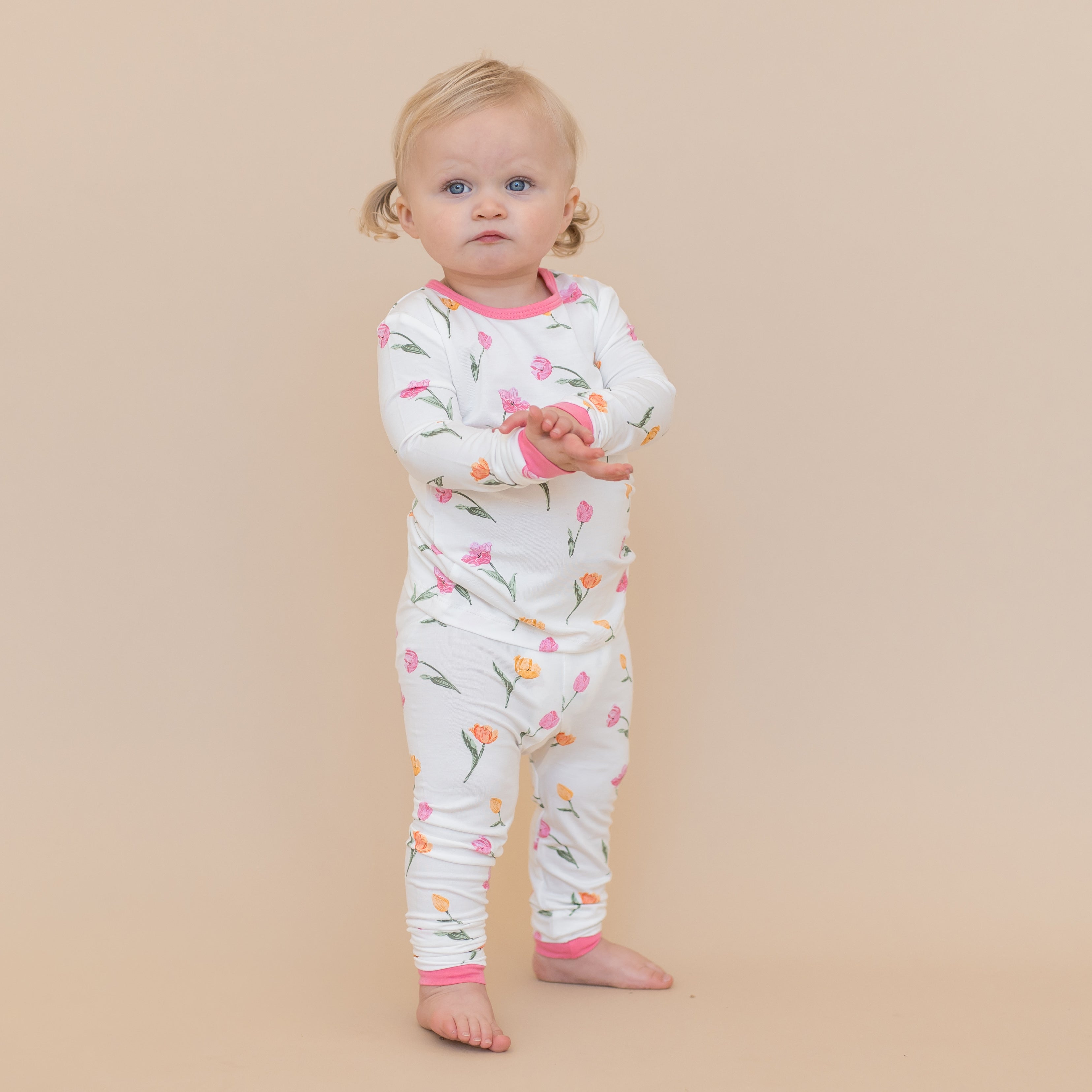 Young toddler standing in front of a light beige background wearing the Long Sleeve Pajamas in Tulip