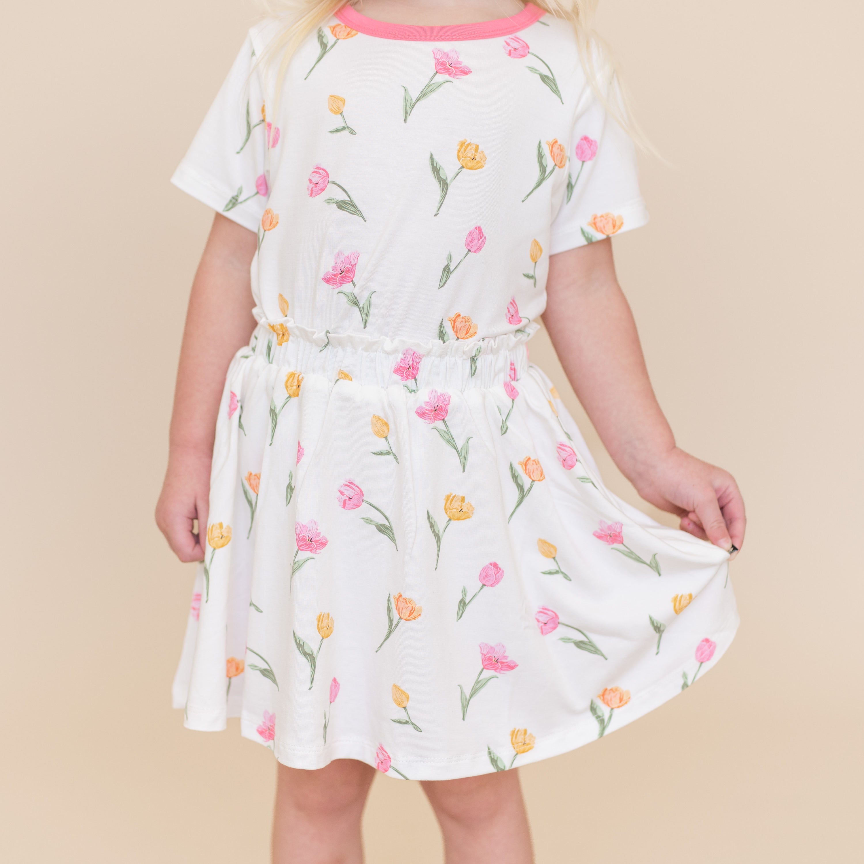 Young girl wearing the Toddler Skort in Tulip holding the hem of the skirt out paired with a matching basic tee