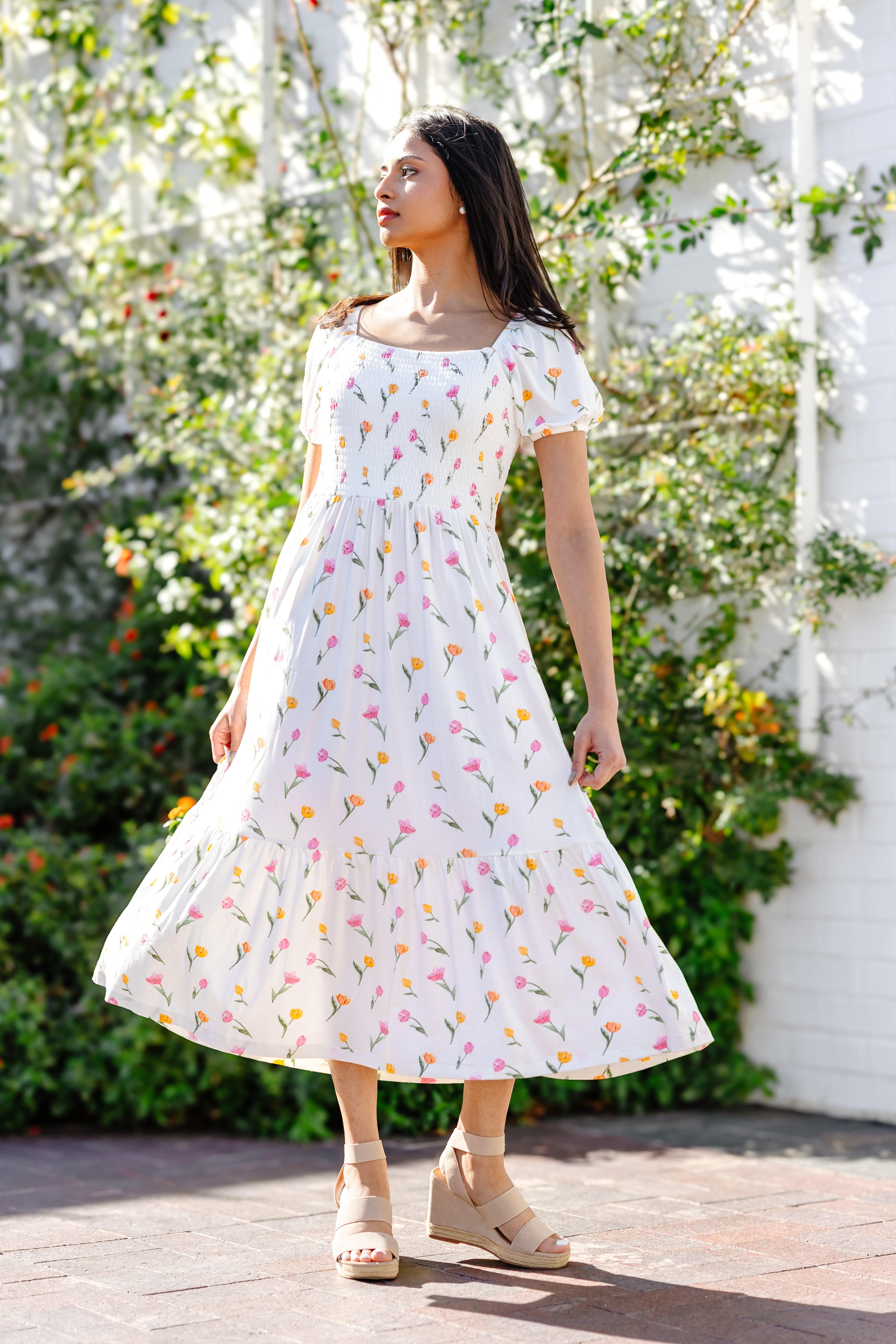 Female model turning wearing the Women’s Smocked Dress in Tulip showing the twirl in the skirt of the dress