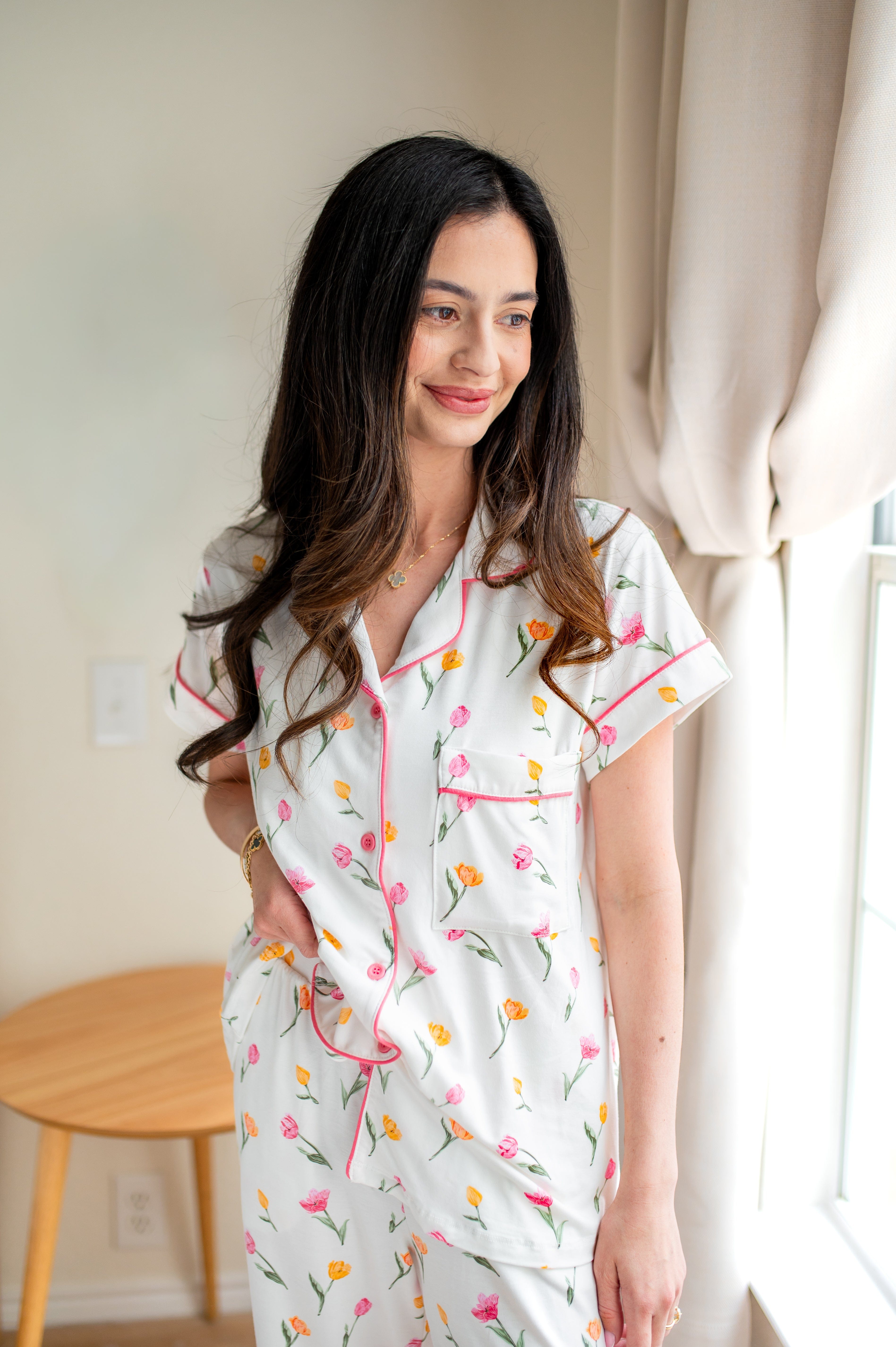 Close up of model wearing the Women's Short Sleeve Cropped Pajama Set in Tulip standing beside a window