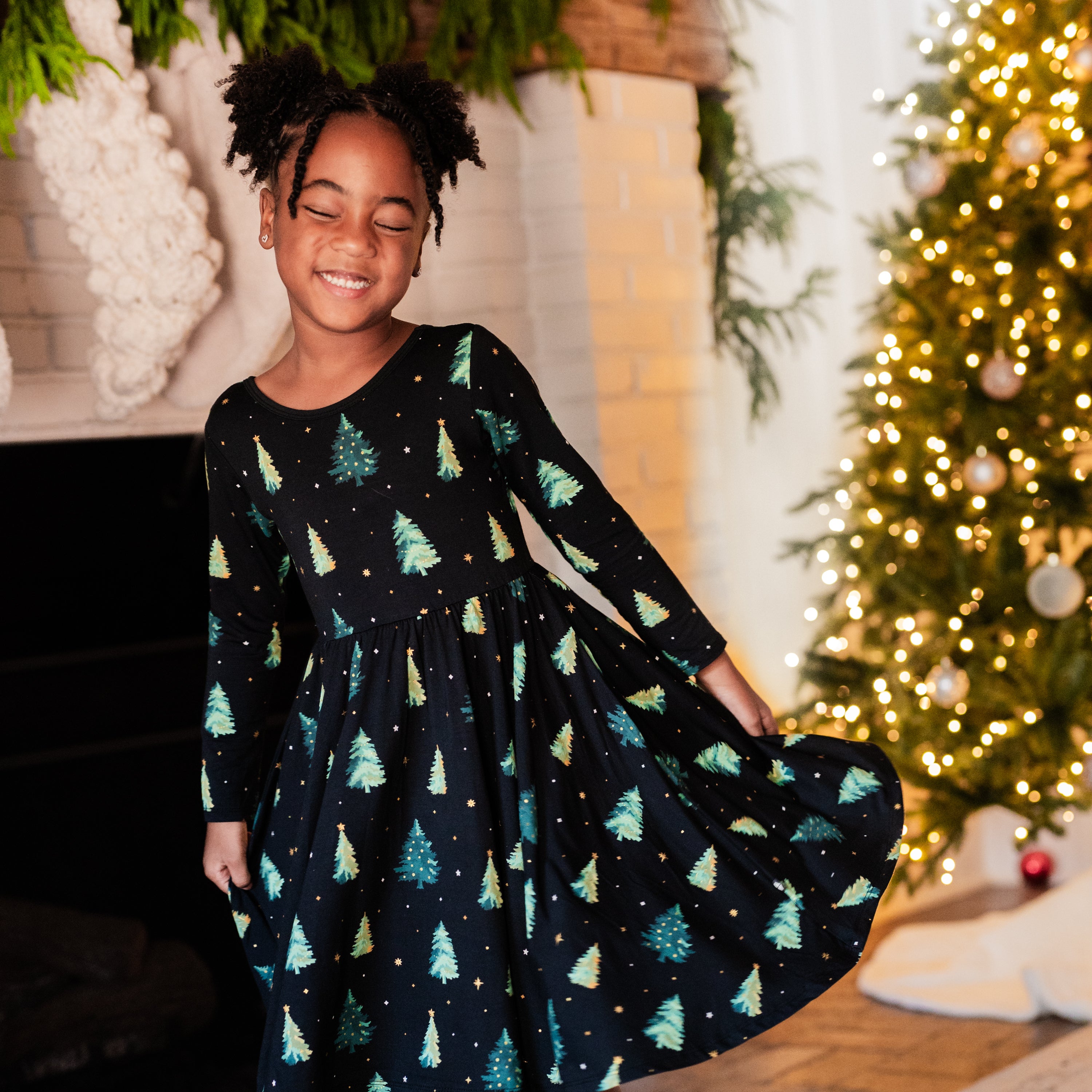 Young girl smiling with her eyes closed wearing the Long Sleeve Twirl Dress in Twinkle Tree