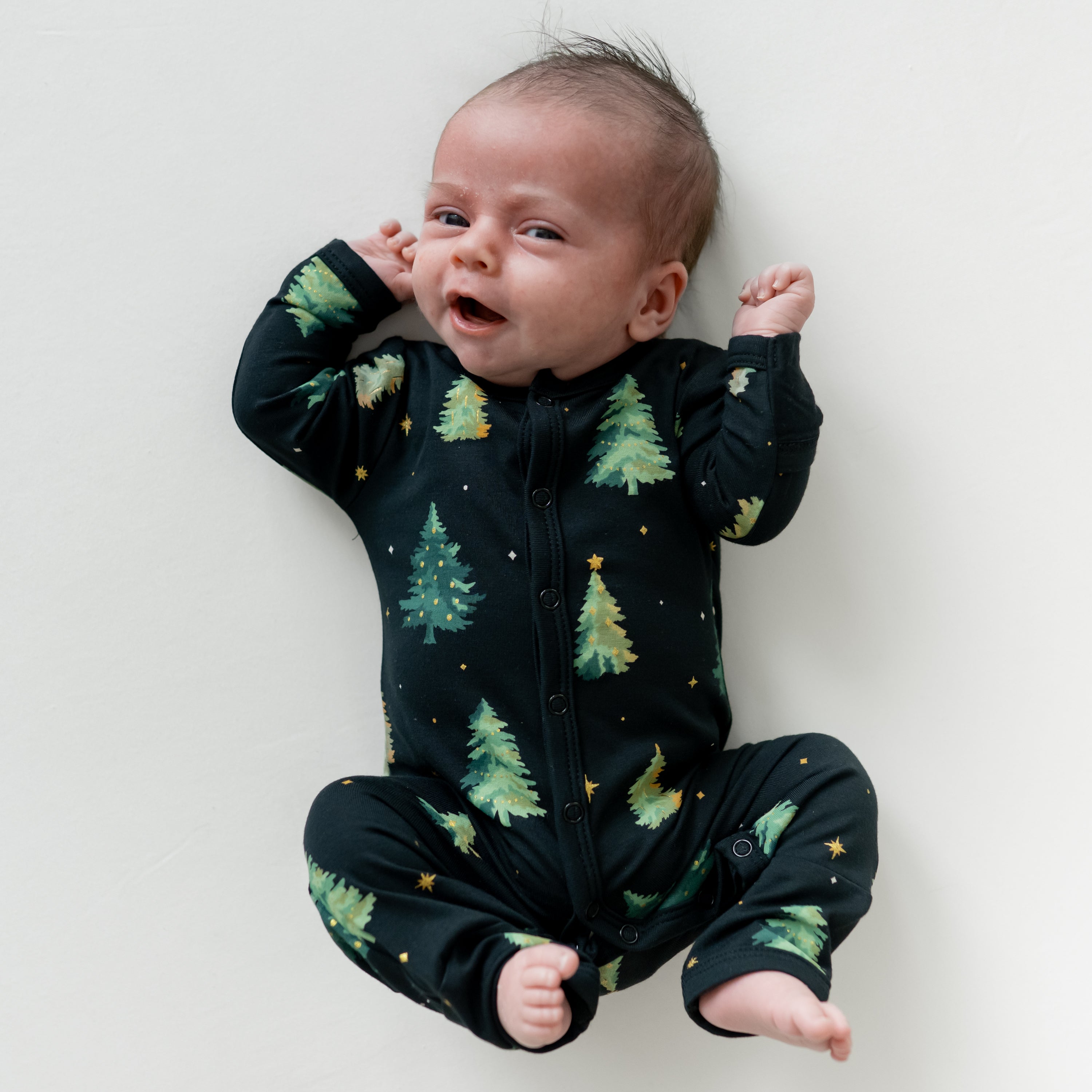 Infant laying down wearing the Romper in Twinkle Tree