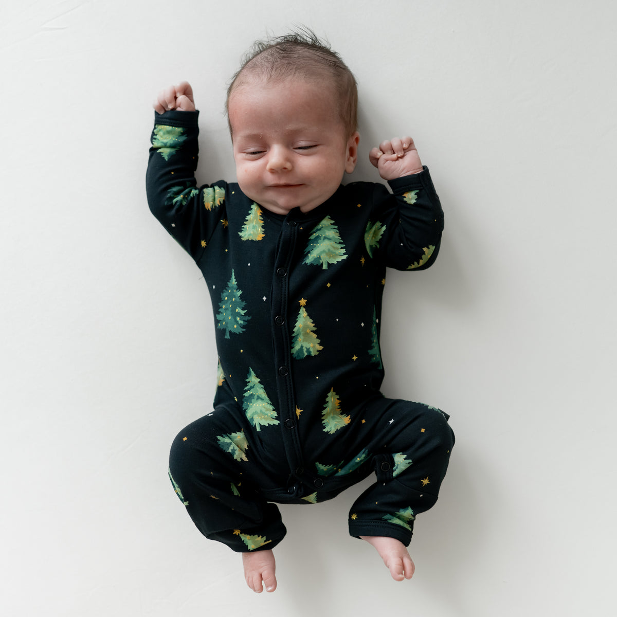 Infant laying down wearing the Romper in Twinkle Tree