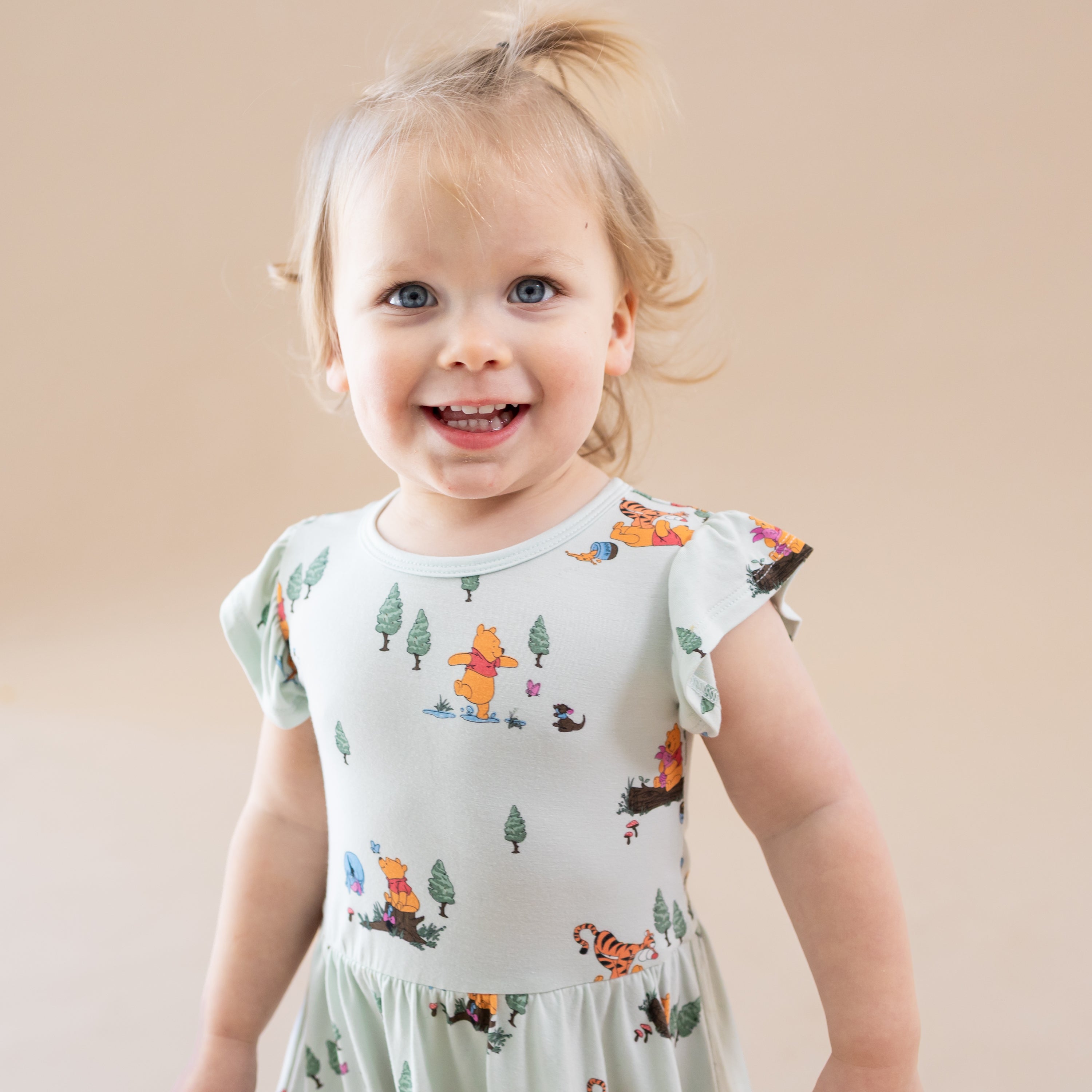 Close up of toddler model wearing the Twirl Bodysuit Dress in Winnie the Pooh Hundred Acre Wood