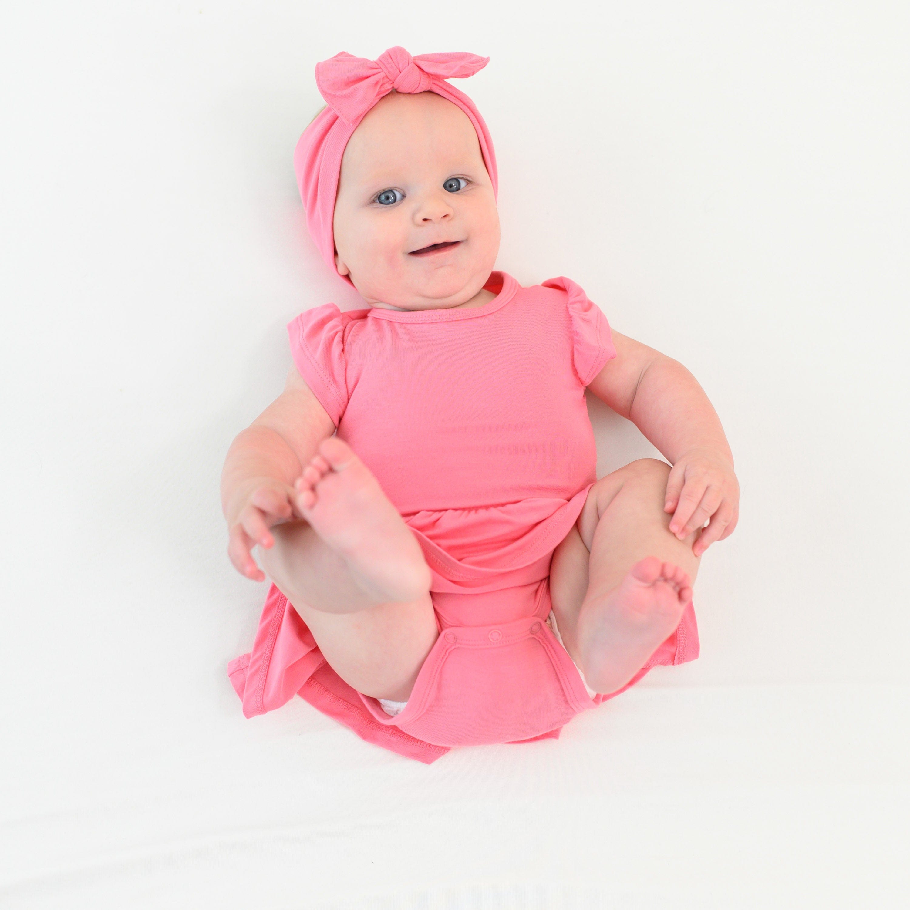 Baby wearing bamboo twirl bodysuit pink dress and bow