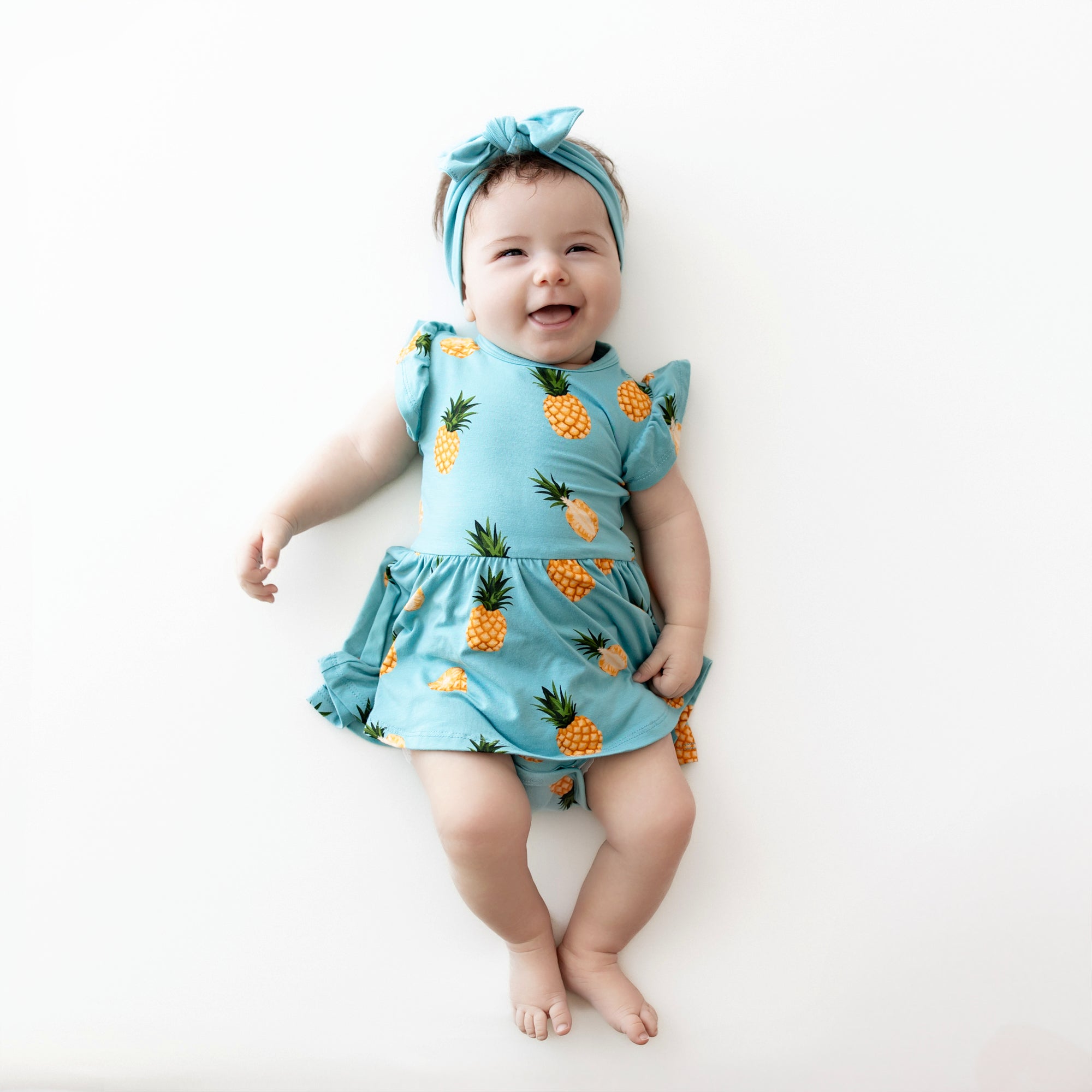 Baby wearing Twirl Bodysuit Dress in Pineapple and makai bow