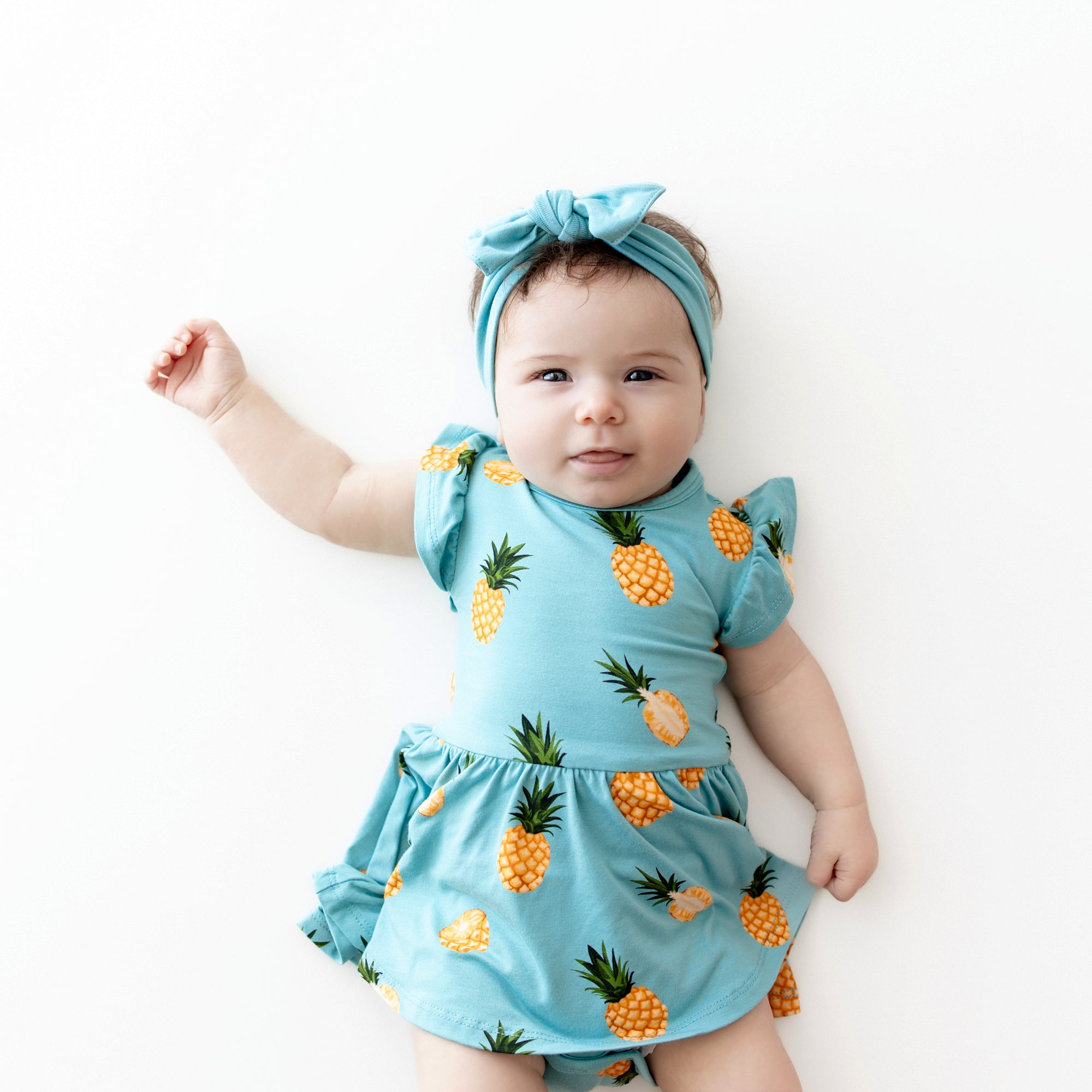 Baby wearing Twirl Bodysuit Dress in Pineapple and makai bow close up