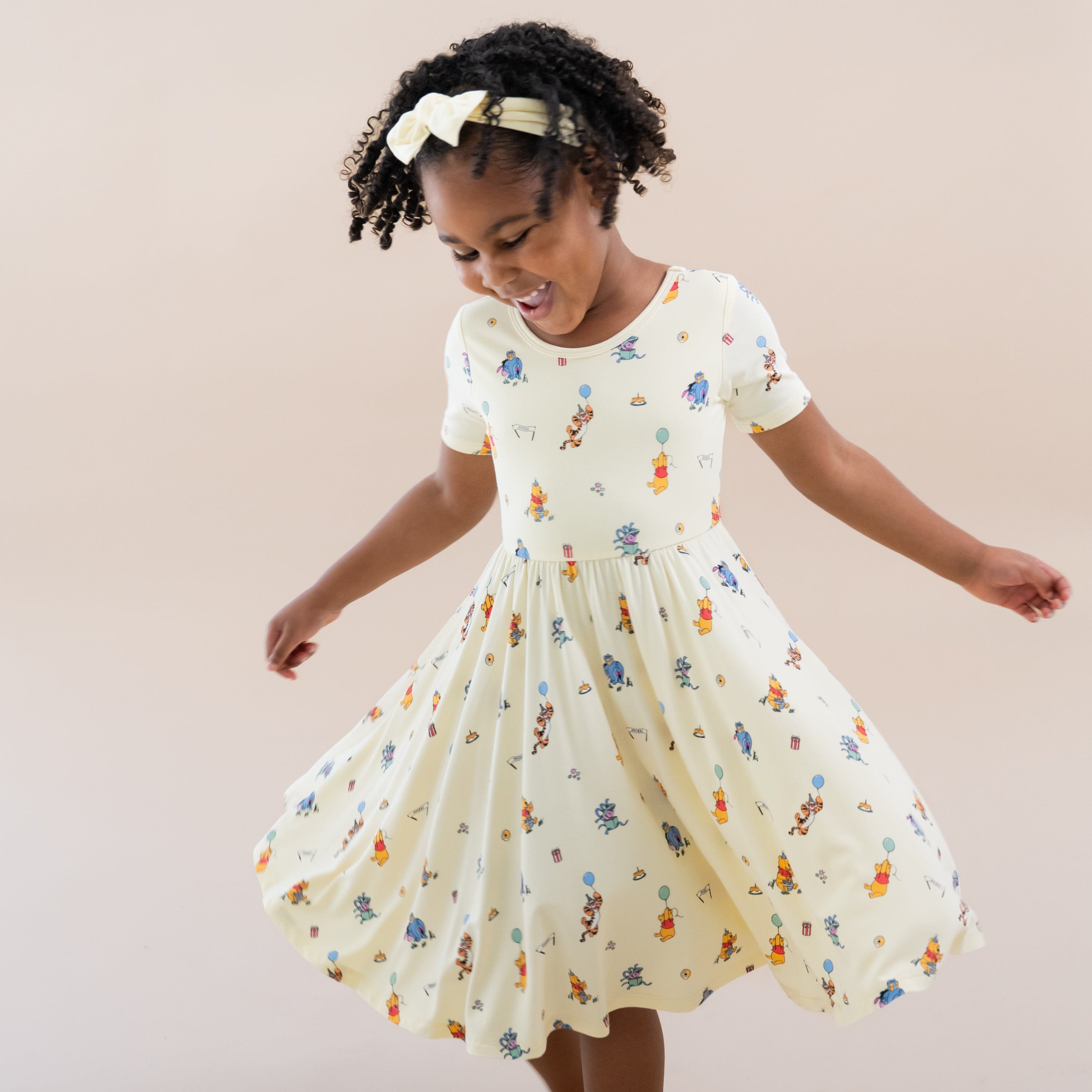 Young girl twirling wearing the Twirl Dress in Winnie the Pooh Celebration