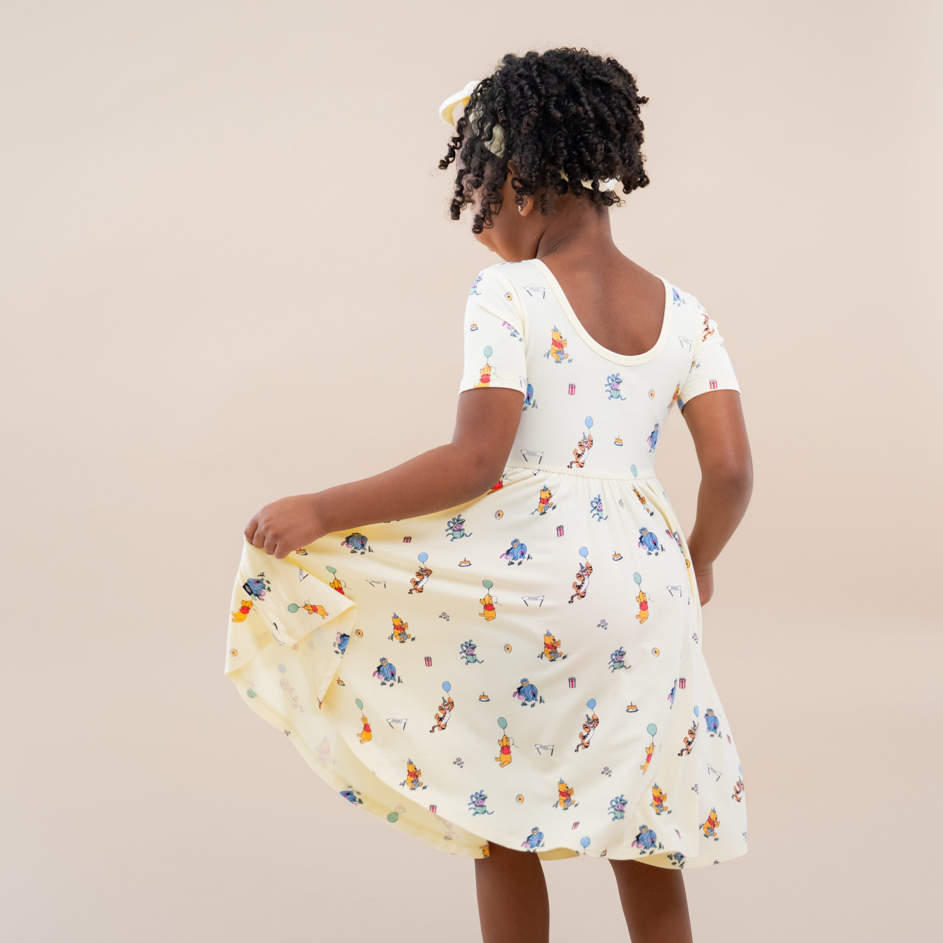 The back of the Twirl Dress in Winnie the Pooh Celebration showing the ballerina back shown on a young girl