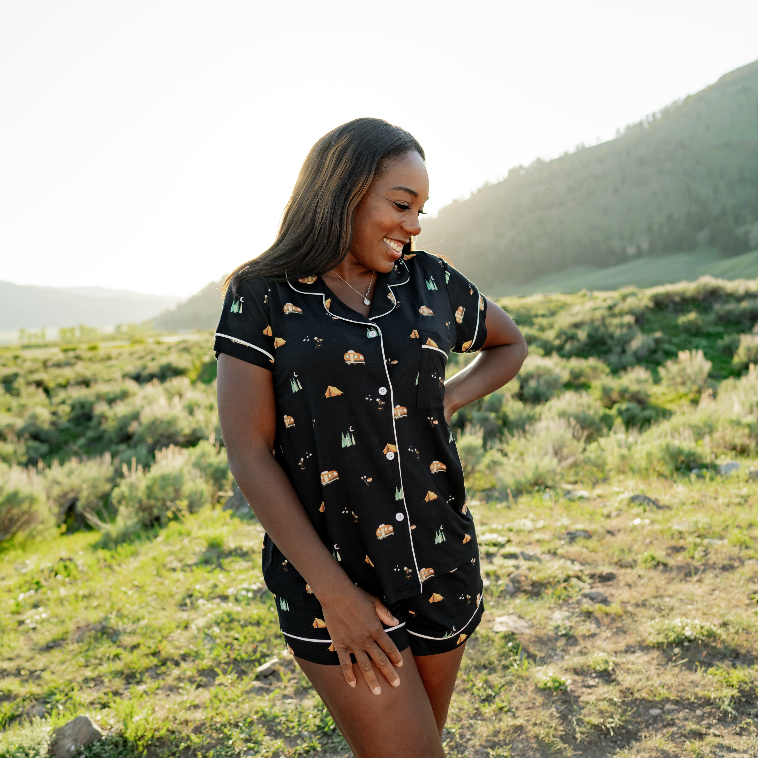 Smiling model looking down to the side wearing the Women's Short Sleeve Pajama Set in Under the Stars while standing in a field in a National Park