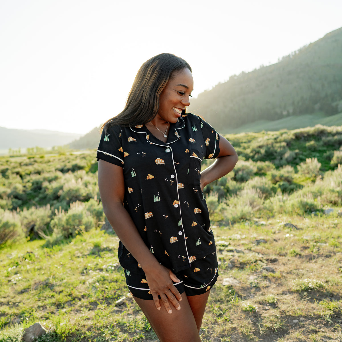 Smiling model looking down to the side wearing the Women's Short Sleeve Pajama Set in Under the Stars while standing in a field in a National Park