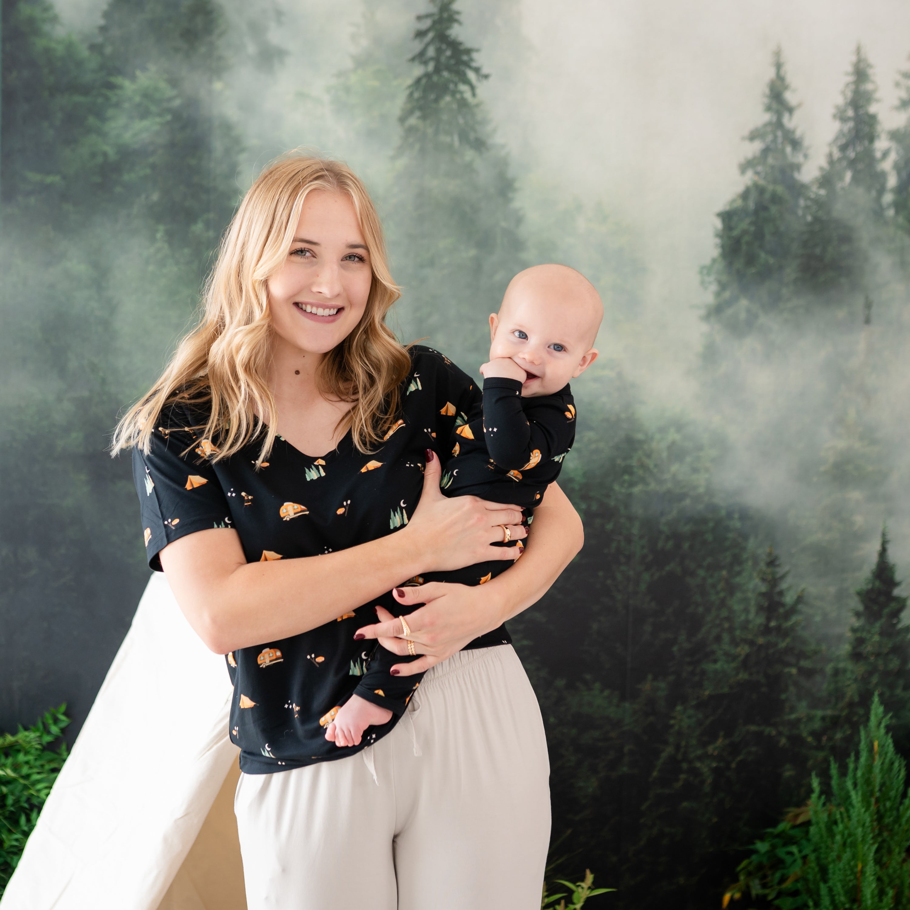 Mother wearing the Women's Relaxed Fit V-Neck in Under the stars holding her infant wearing a matching zippered romper