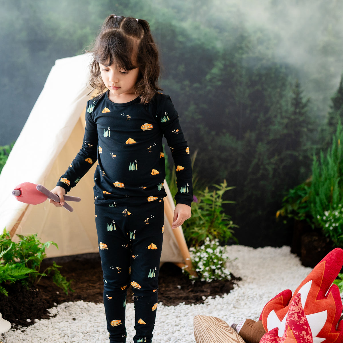 Girl model wearing the Long Sleeve Pajamas in Under the Stars in front of a camping back drop