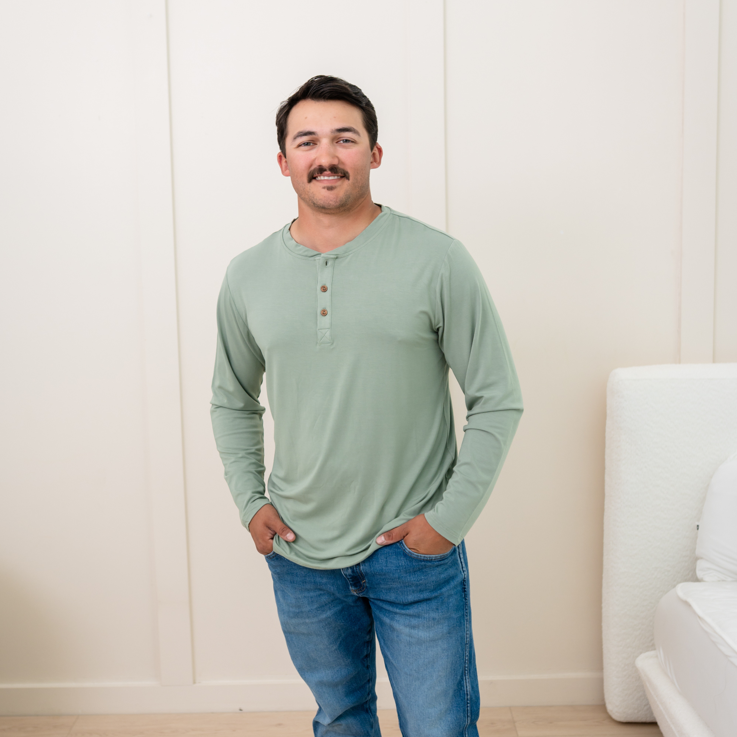 Model wearing Men's Long Sleeve Henley Top in Thyme and jeans