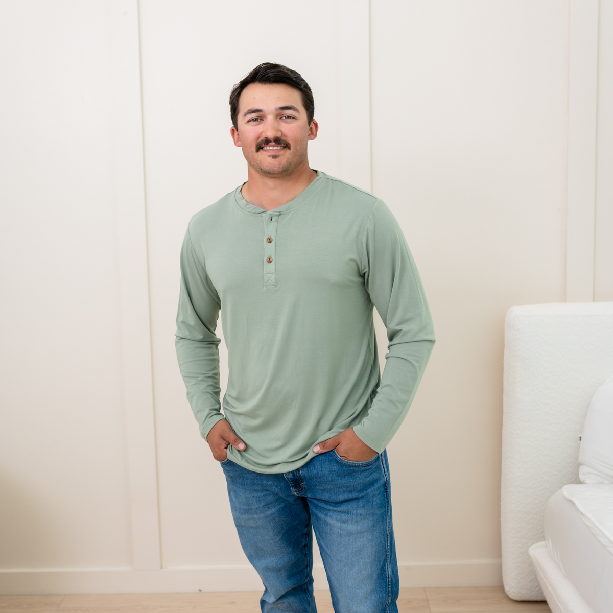 Model wearing Men's Long Sleeve Henley Top in Thyme and jeans