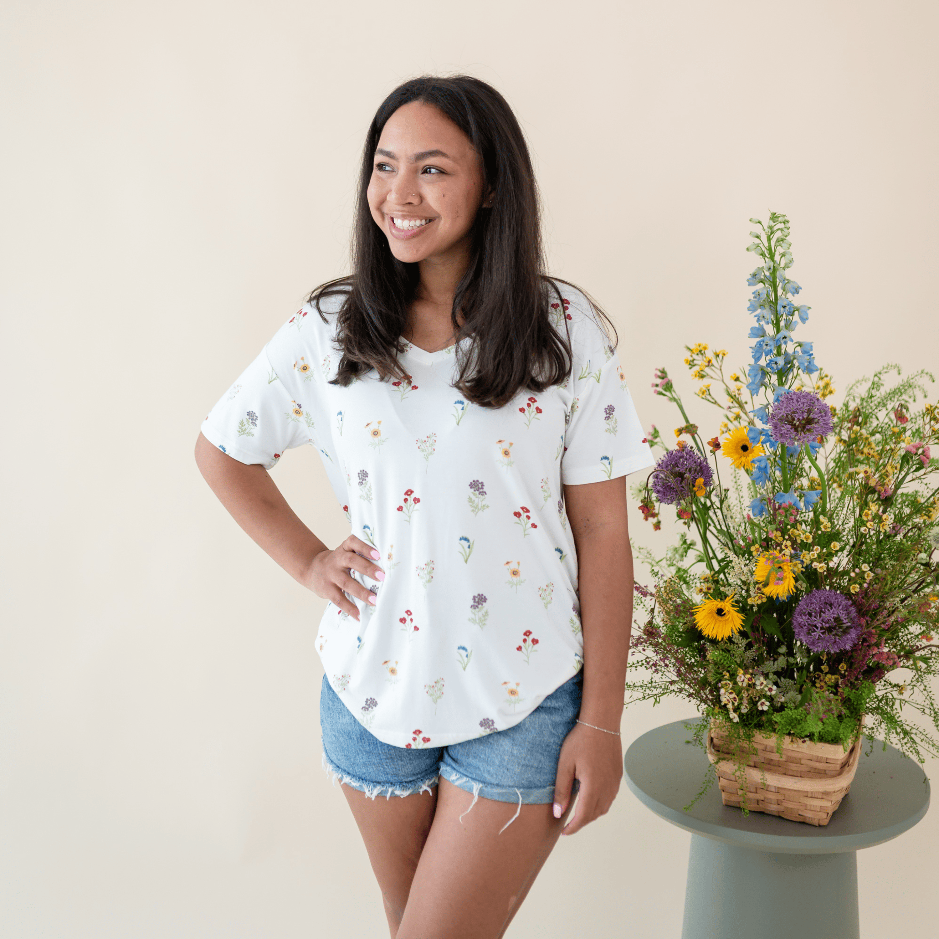 Woman modeling Women’s Relaxed Fit V-Neck in Wildflower next to floral arrangement